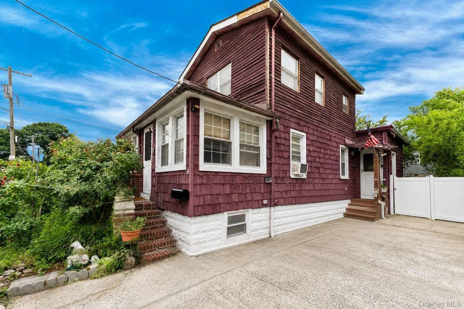 Two-story residence featuring deep red shingle and horizontal siding, white trim, and multiple windows Two-story residence featuring deep red shingle and horizontal siding, white trim, and multiple windows