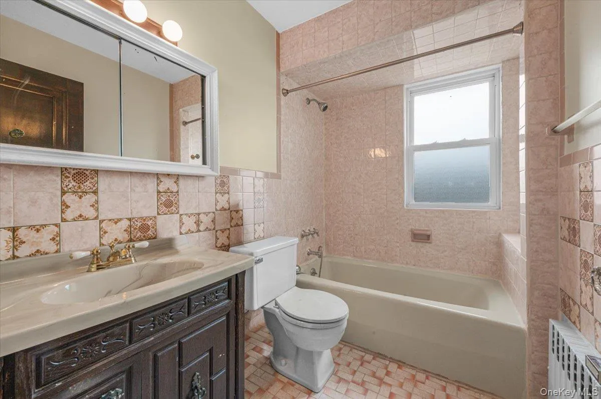 Bathroom featuring a vanity with an integrated sink, medicine cabinet, and a built-in bathtub with an overhead shower. Bathroom featuring a vanity with an integrated sink, medicine cabinet, and a built-in bathtub with an overhead shower.