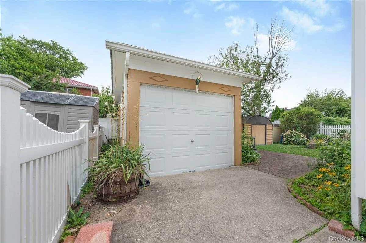 Detached single-car garage featuring a white panel door and concrete driveway Detached single-car garage featuring a white panel door and concrete driveway