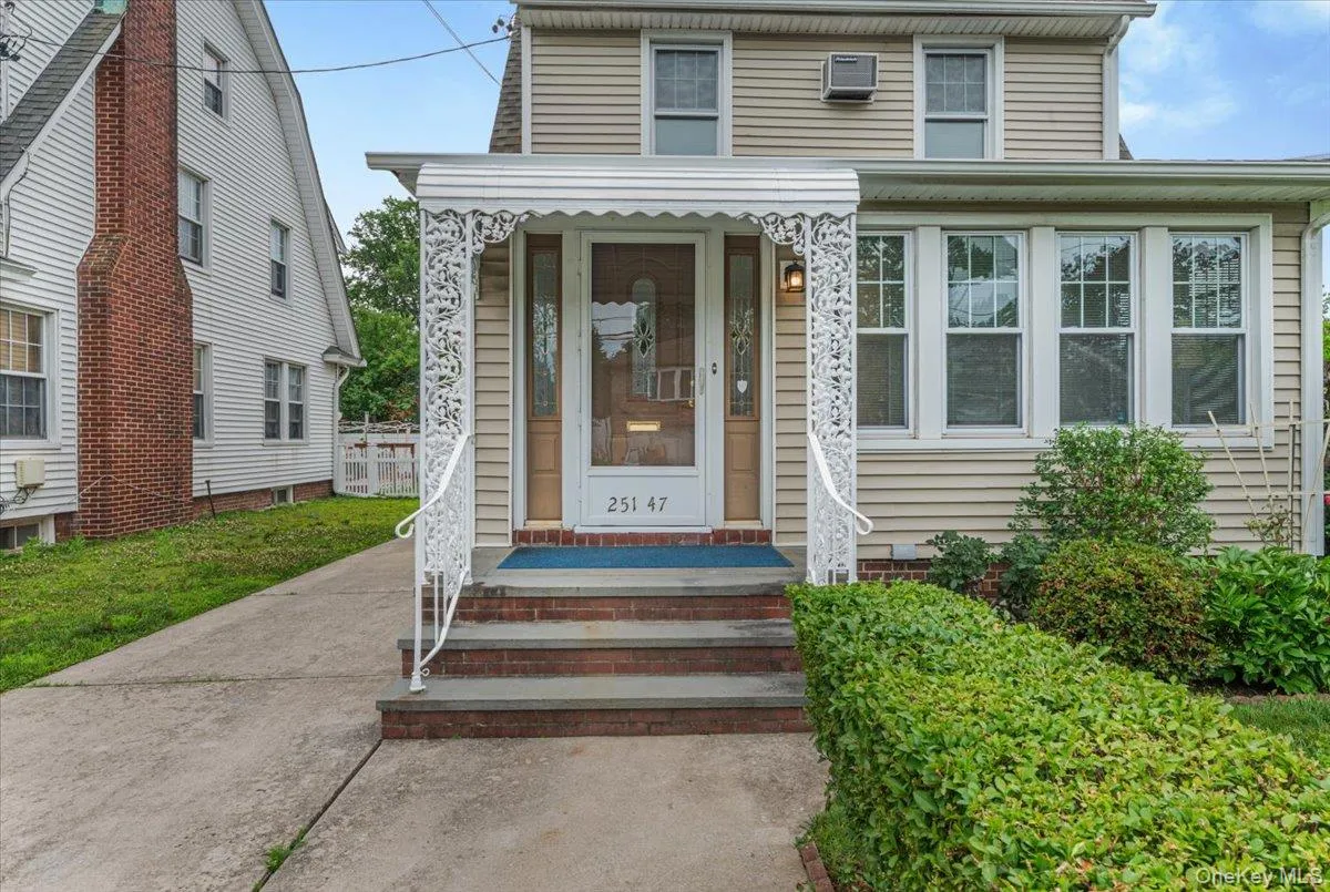 Siding exterior featuring a prominent front entrance with an ornamental metal awning and handrail Siding exterior featuring a prominent front entrance with an ornamental metal awning and handrail