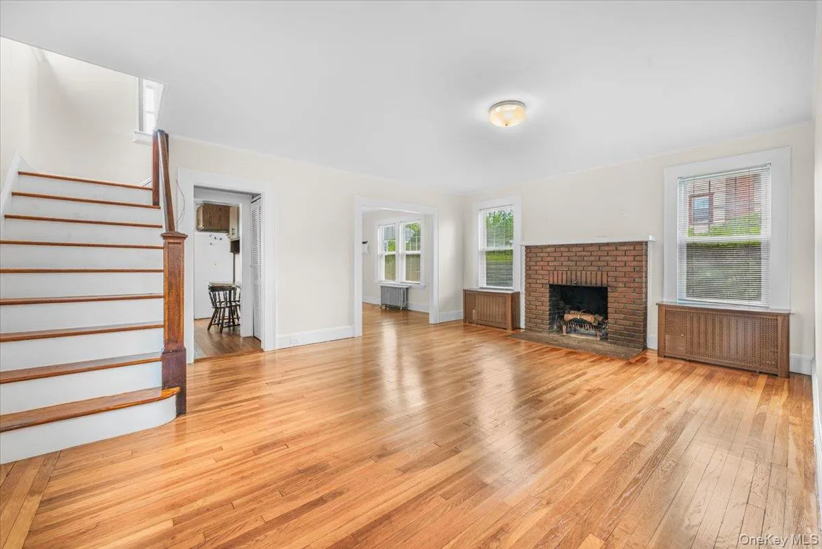 Large living room with wood burning fireplace, 3 windows allowing generous natural light, Hardwood flooring. Large living room with wood burning fireplace, 3 windows allowing generous natural light, Hardwood flooring.