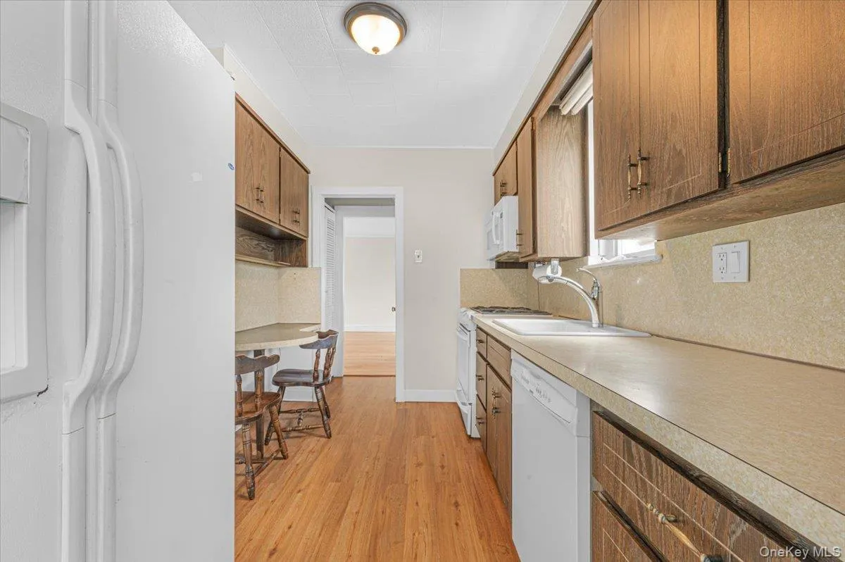 Kitchen featuring wood-finish flooring, wood cabinetry, built-in appliances, and a window above the sink Kitchen featuring wood-finish flooring, wood cabinetry, built-in appliances, and a window above the sink