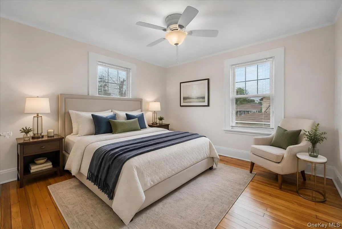 Spacious bedroom with Hardwood flooring throughout this room featuring two windows with venetian blinds, white baseboards, and a ceiling fan with integrated lighting Spacious bedroom with Hardwood flooring throughout this room featuring two windows with venetian blinds, white baseboards, and a ceiling fan with integrated lighting