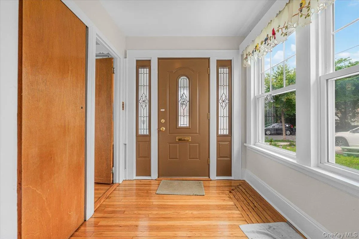 Entryway featuring a paneled door with decorative glass inserts, sidelight windows with matching decorative glass, and wood-finish flooring Entryway featuring a paneled door with decorative glass inserts, sidelight windows with matching decorative glass, and wood-finish flooring