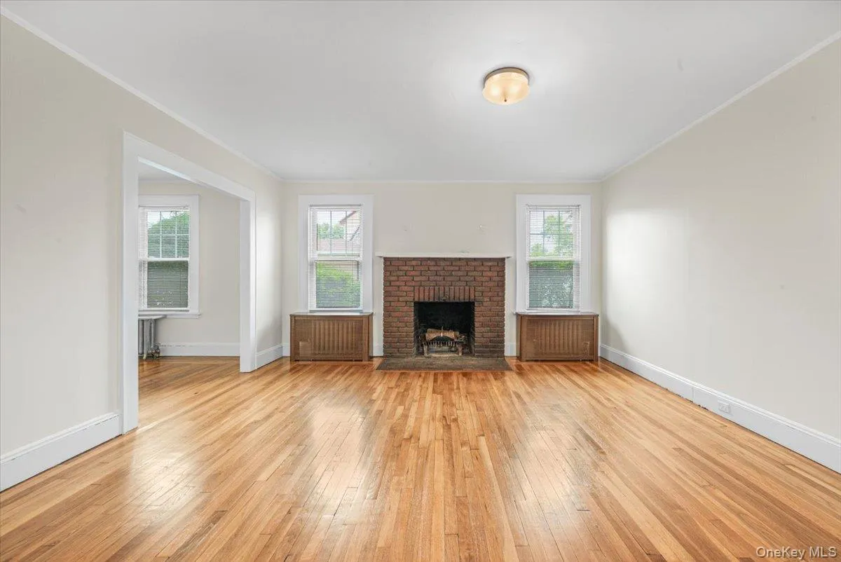 Living room with hardwood flooring, wood baseboard moldings, new windows, steam heating, cast iron radiators Living room with hardwood flooring, wood baseboard moldings, new windows, steam heating, cast iron radiators