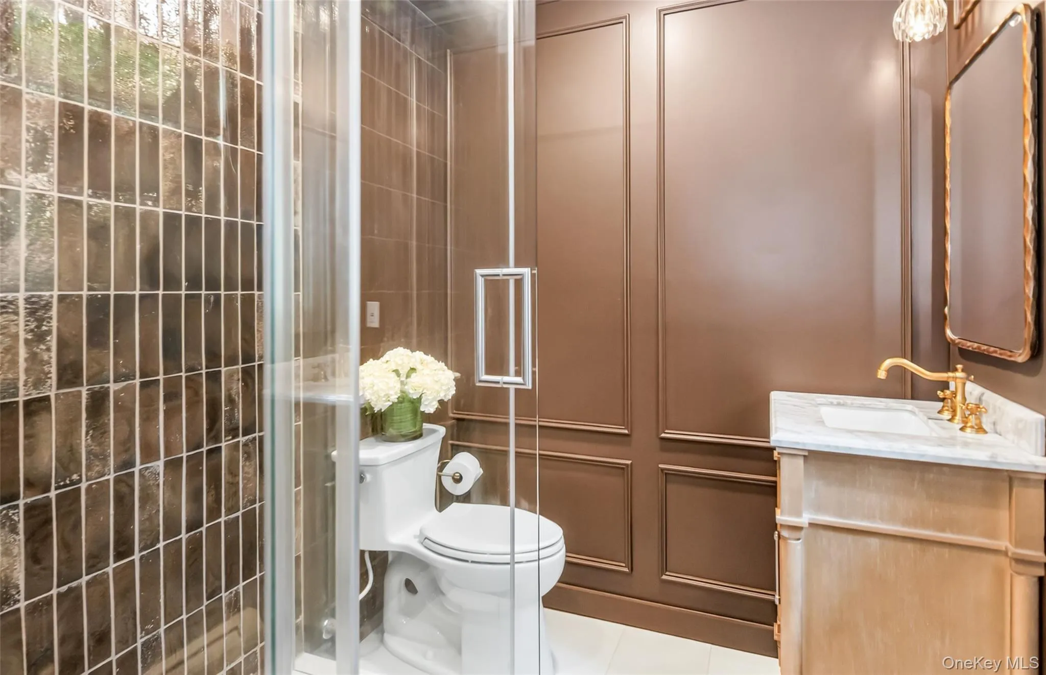 A spa-worthy bath wrapped in rich paneling, marble, and brass, with a glazed tile shower. A spa-worthy bath wrapped in rich paneling, marble, and brass, with a glazed tile shower.