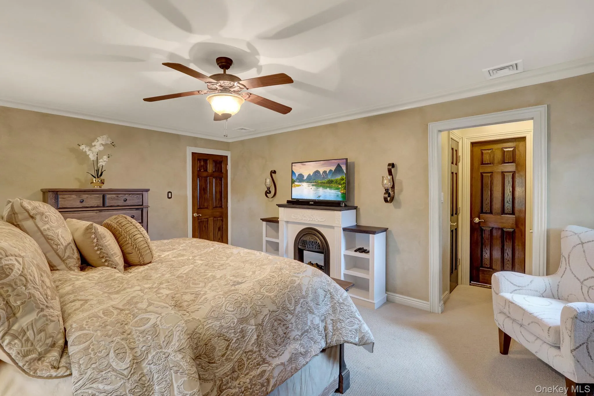 Room featuring a built-in decorative fireplace, ceiling fan with integrated lighting, and multiple paneled doors Room featuring a built-in decorative fireplace, ceiling fan with integrated lighting, and multiple paneled doors
