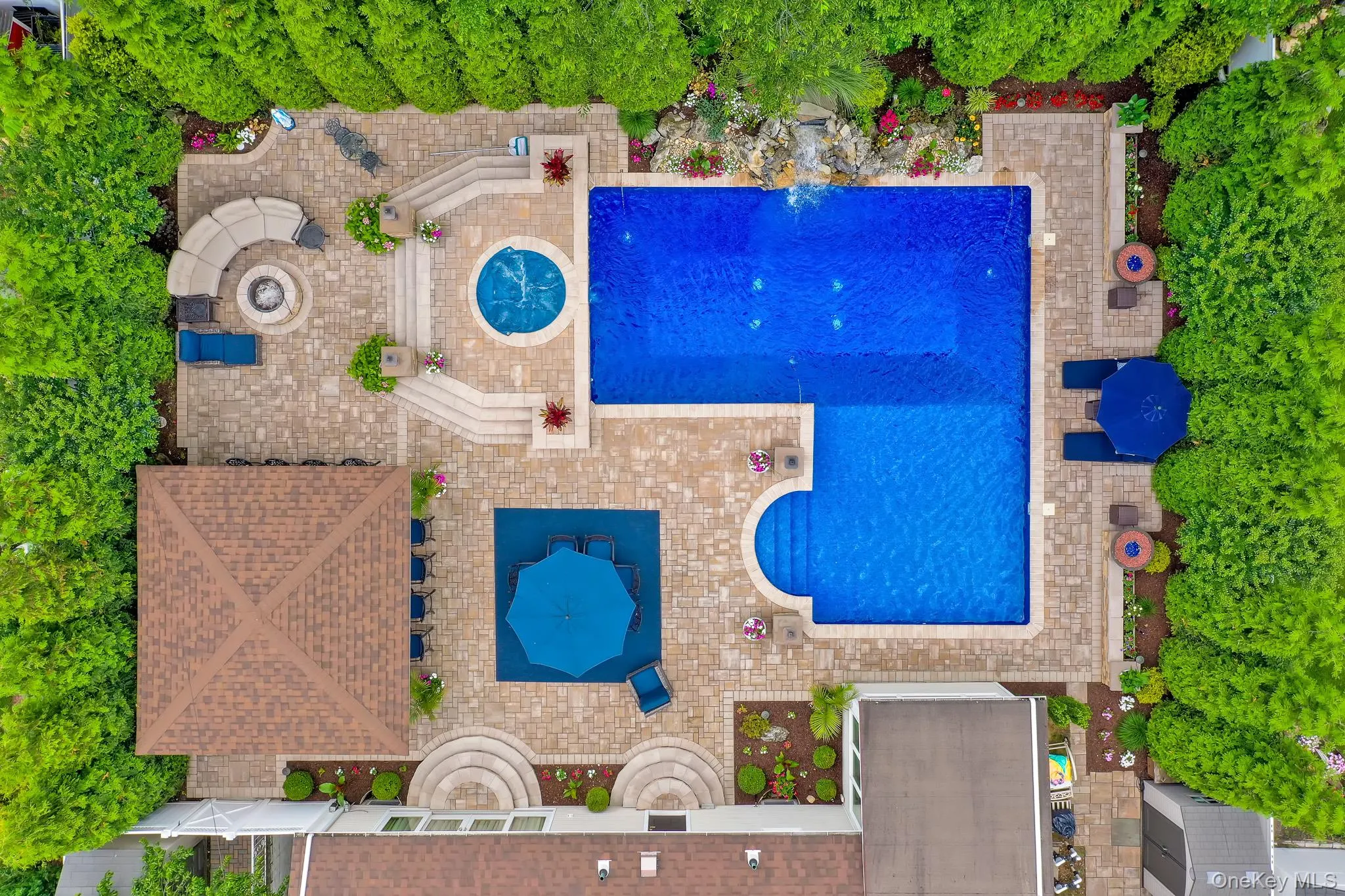 Expansive outdoor living area featuring a rectangular pool, integrated spa, and a gazebo with a shingled roof Expansive outdoor living area featuring a rectangular pool, integrated spa, and a gazebo with a shingled roof