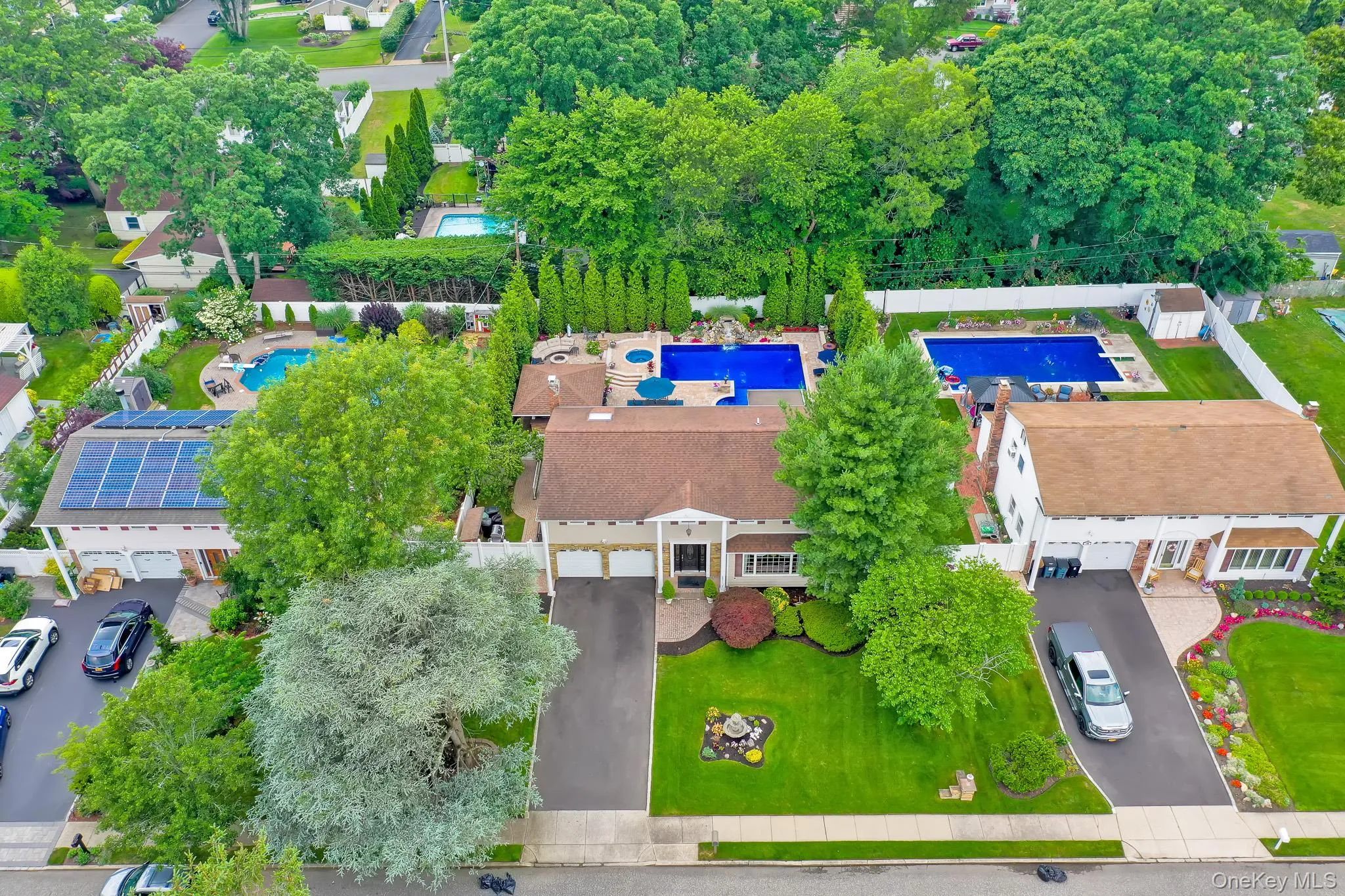 Expansive backyard featuring a large in-ground swimming pool, surrounding patio area, and mature perimeter landscaping Expansive backyard featuring a large in-ground swimming pool, surrounding patio area, and mature perimeter landscaping