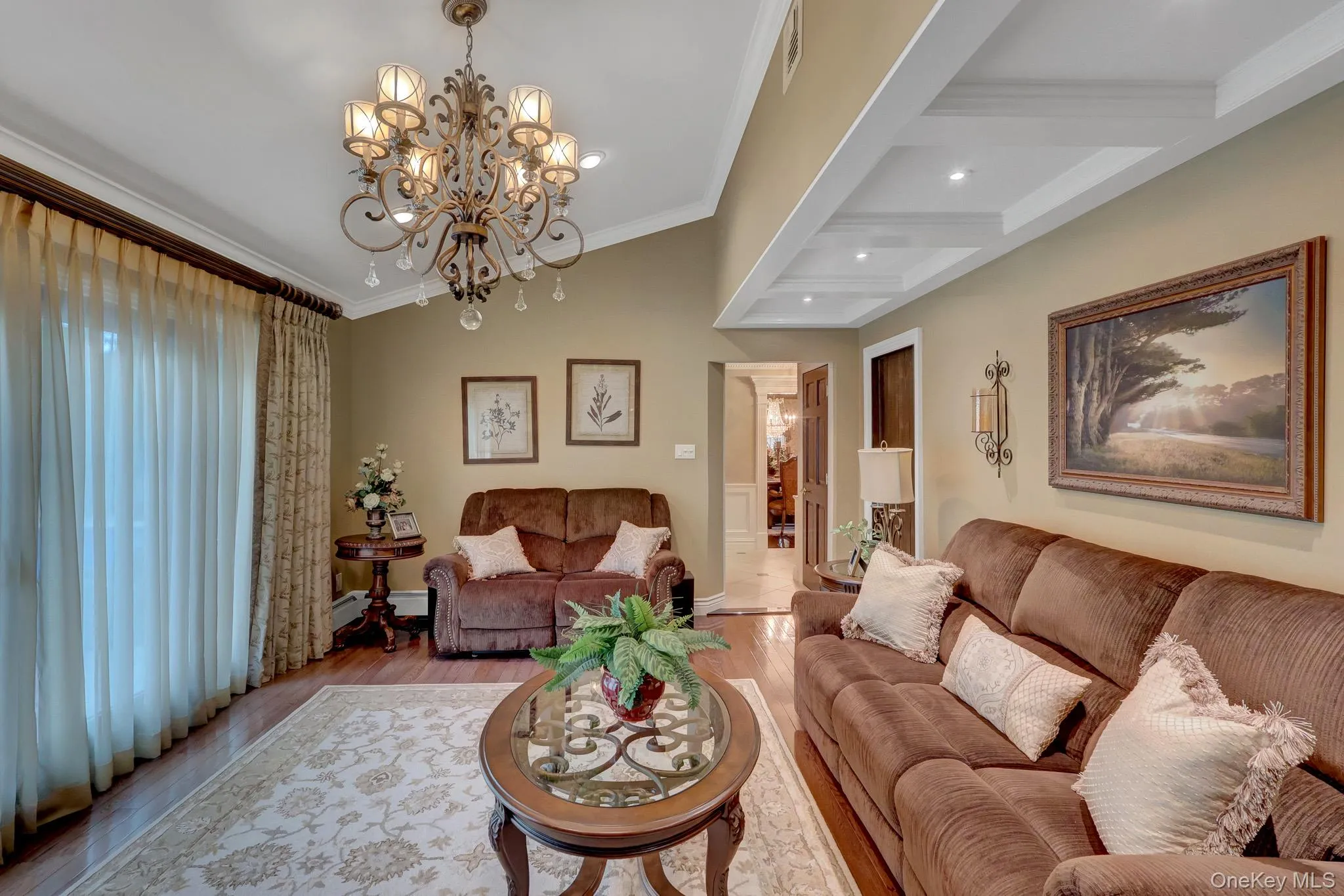 Living area featuring wood-finish flooring, a decorative chandelier, and a coffered ceiling with recessed lighting Living area featuring wood-finish flooring, a decorative chandelier, and a coffered ceiling with recessed lighting