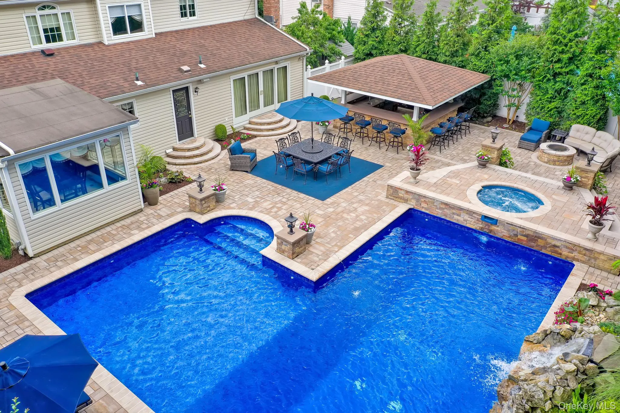 Expansive paver patio featuring a multi-level swimming pool with integrated spa Expansive paver patio featuring a multi-level swimming pool with integrated spa