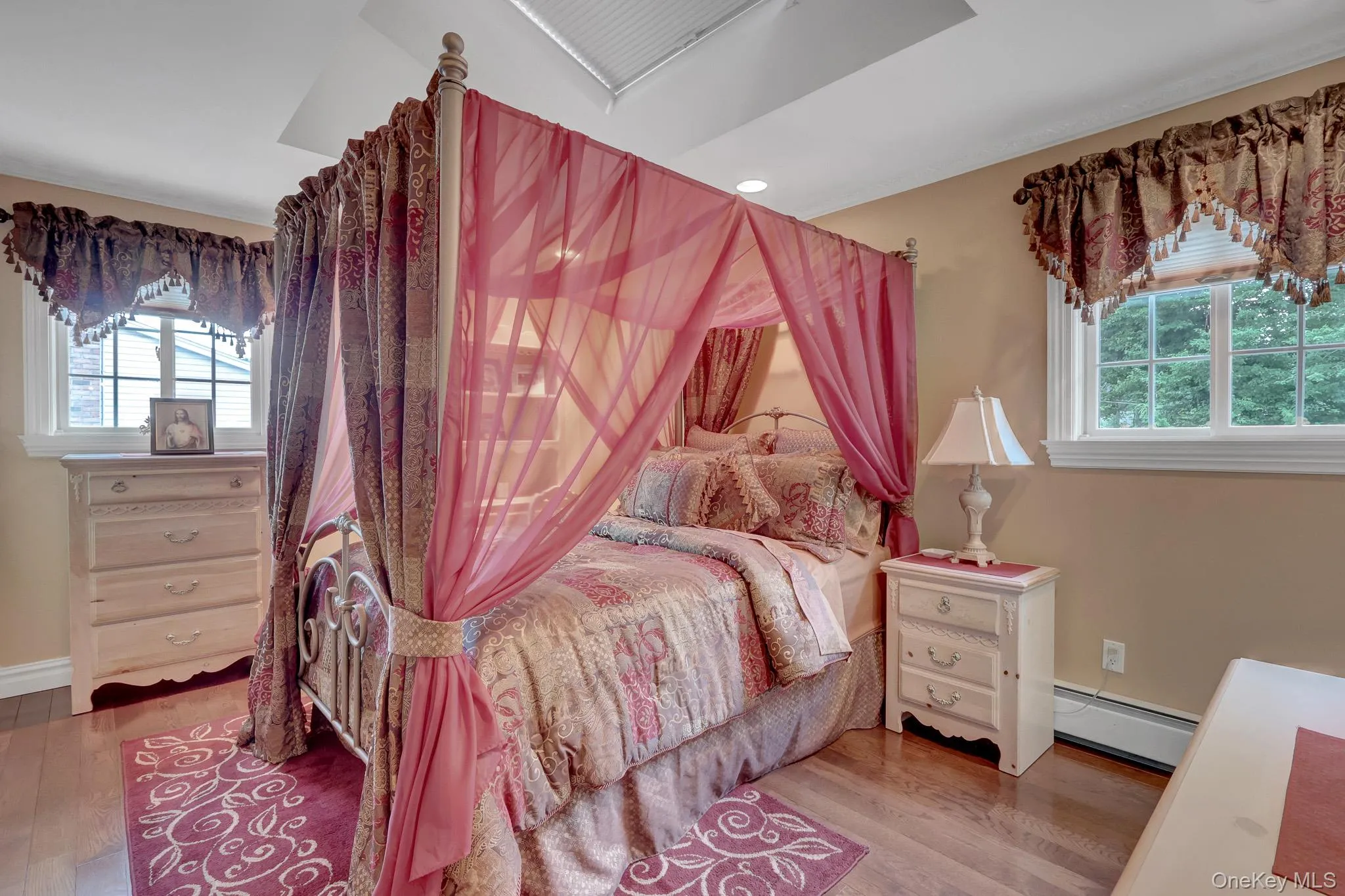 Hardwood flooring throughout featuring a ceiling tray with recessed lighting and a skylight Hardwood flooring throughout featuring a ceiling tray with recessed lighting and a skylight