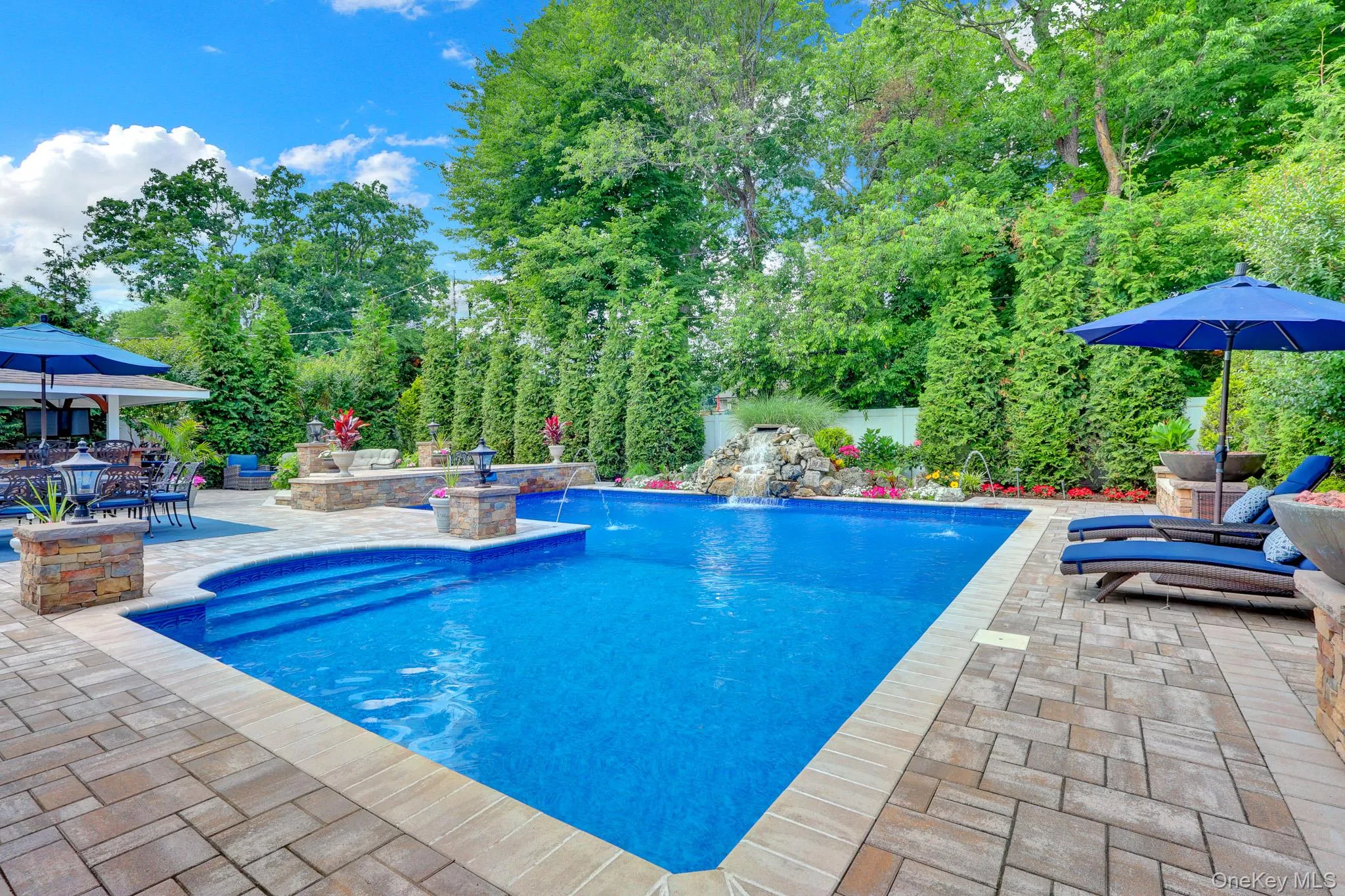 In-ground pool featuring a waterfall, multiple water features, and integrated steps In-ground pool featuring a waterfall, multiple water features, and integrated steps