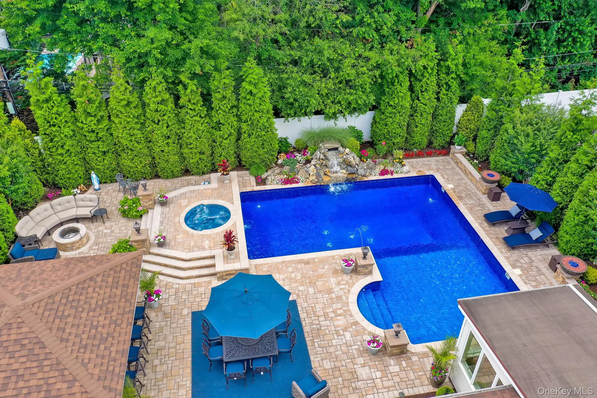 Expansive paved patio featuring an in-ground swimming pool, integrated spa, and waterfall Expansive paved patio featuring an in-ground swimming pool, integrated spa, and waterfall