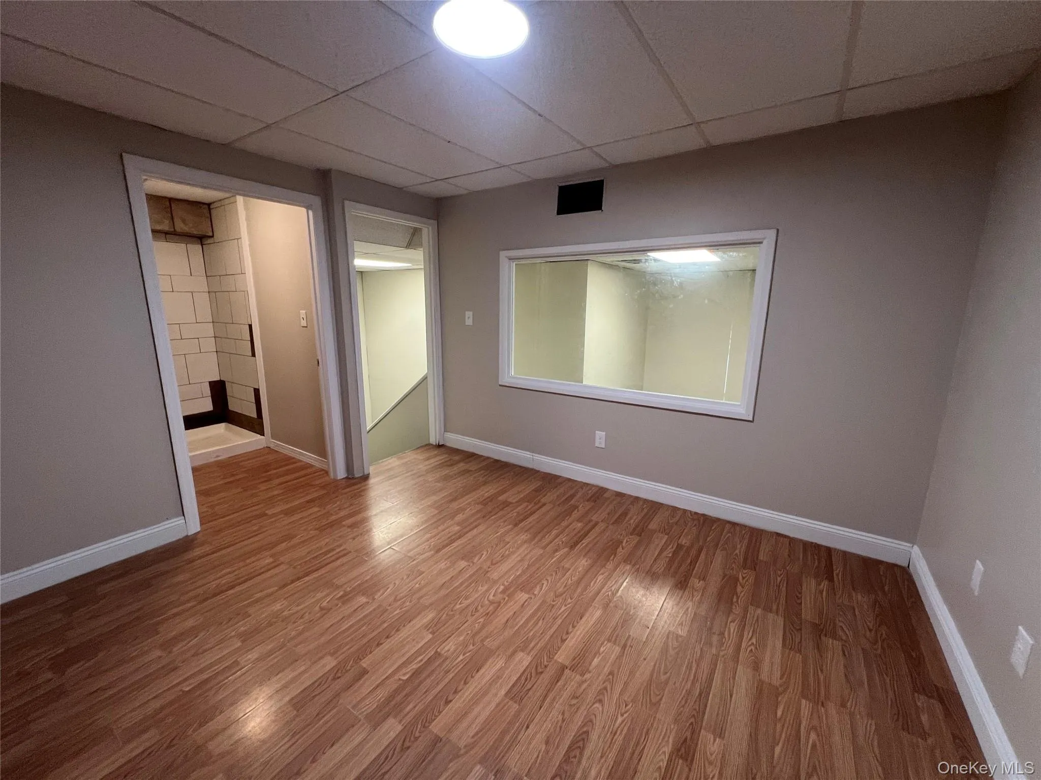 Unfurnished bedroom with a paneled ceiling, baseboards, visible vents, and wood finished floors Unfurnished bedroom with a paneled ceiling, baseboards, visible vents, and wood finished floors
