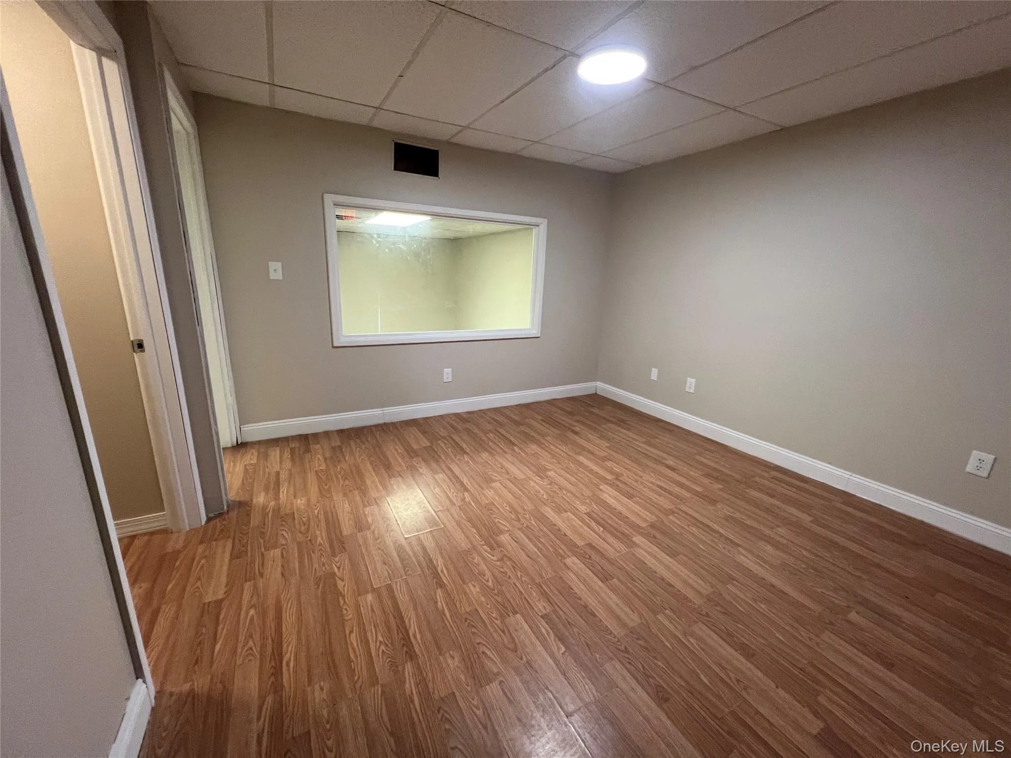 Empty room featuring a paneled ceiling, baseboards, and light wood finished floors Empty room featuring a paneled ceiling, baseboards, and light wood finished floors