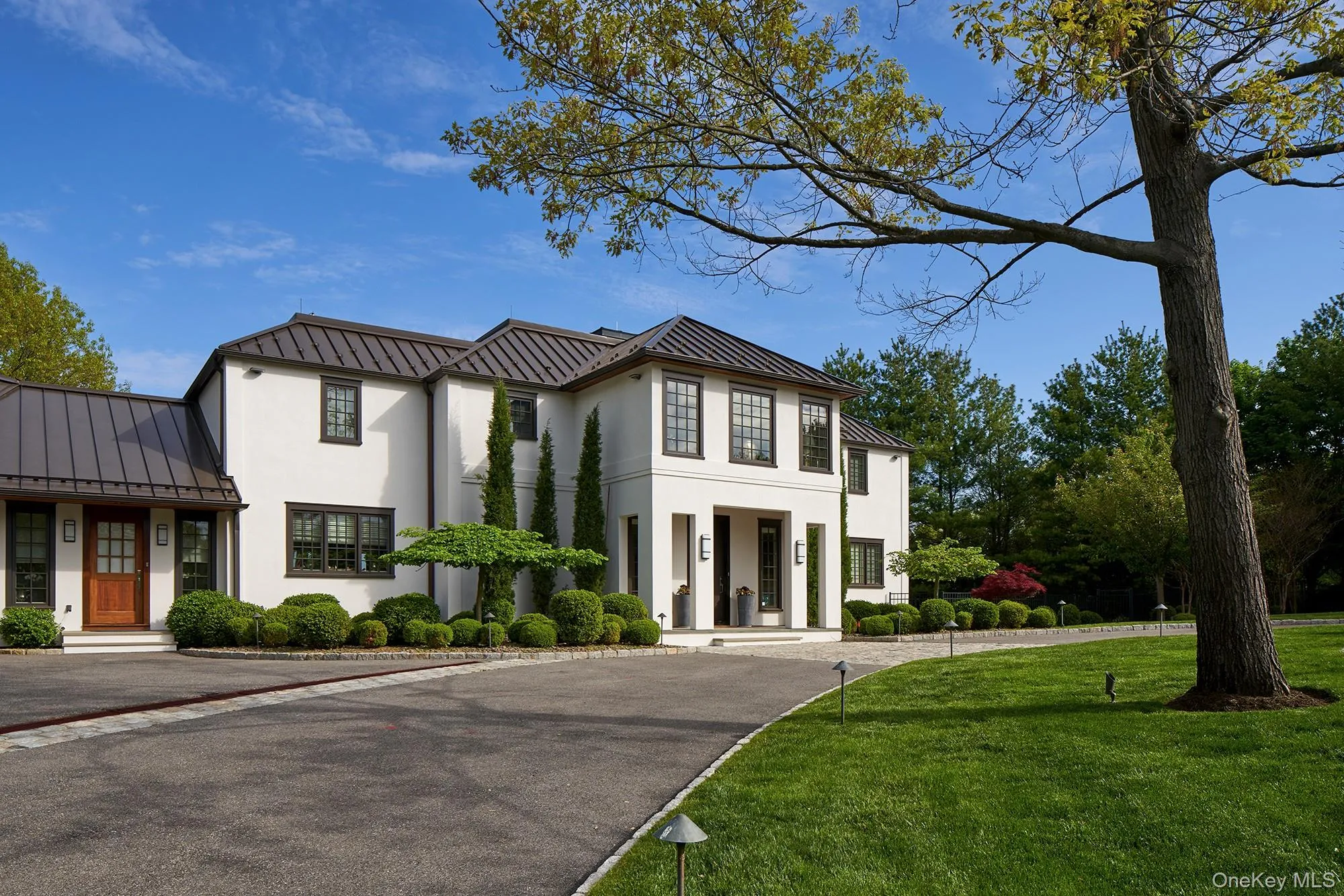 View of front of house with stucco facade, standing seam roof and circular driveway. View of front of house with stucco facade, standing seam roof and circular driveway.