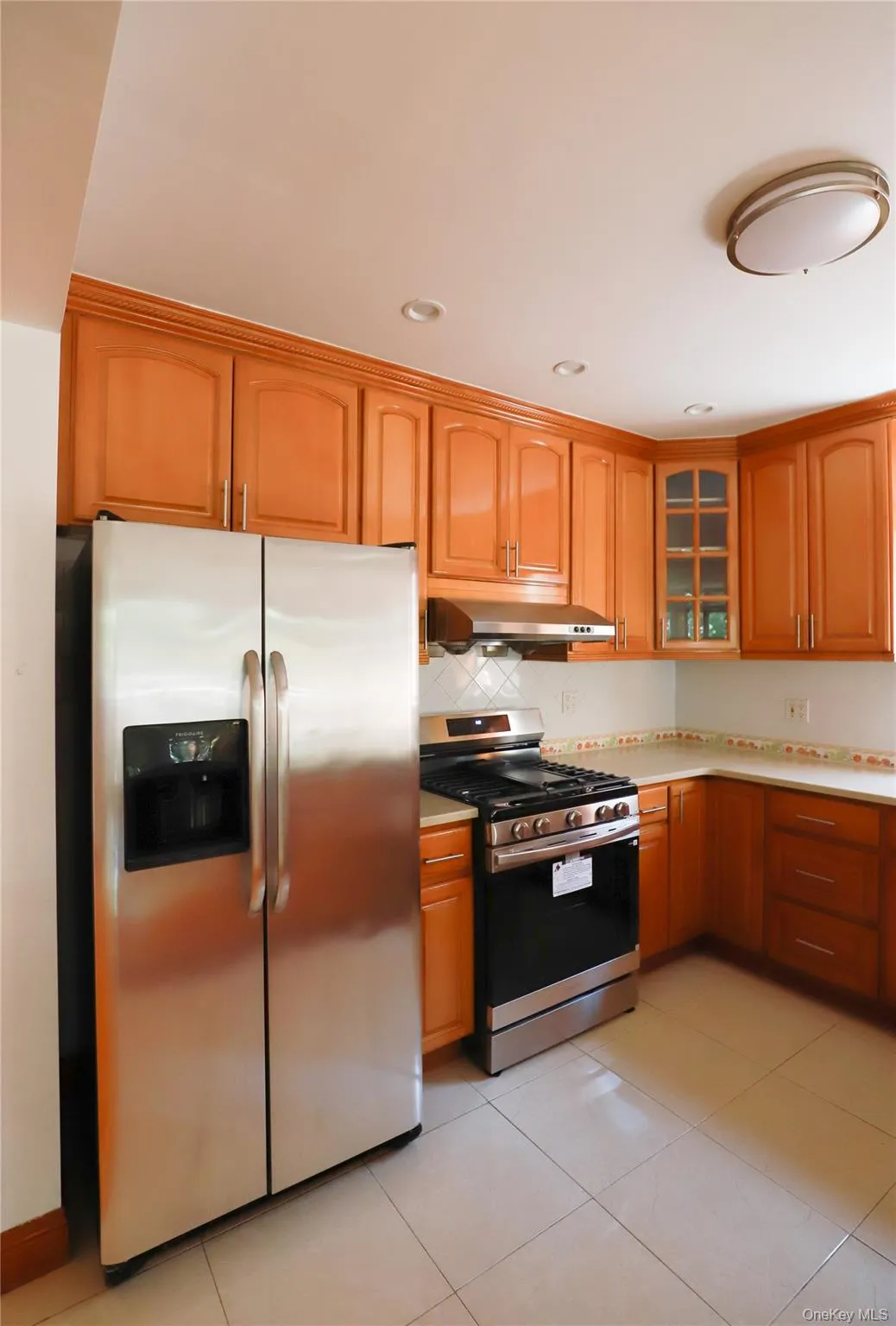 Kitchen featuring wood-finish cabinetry, stainless steel appliances, and tile flooring Kitchen featuring wood-finish cabinetry, stainless steel appliances, and tile flooring