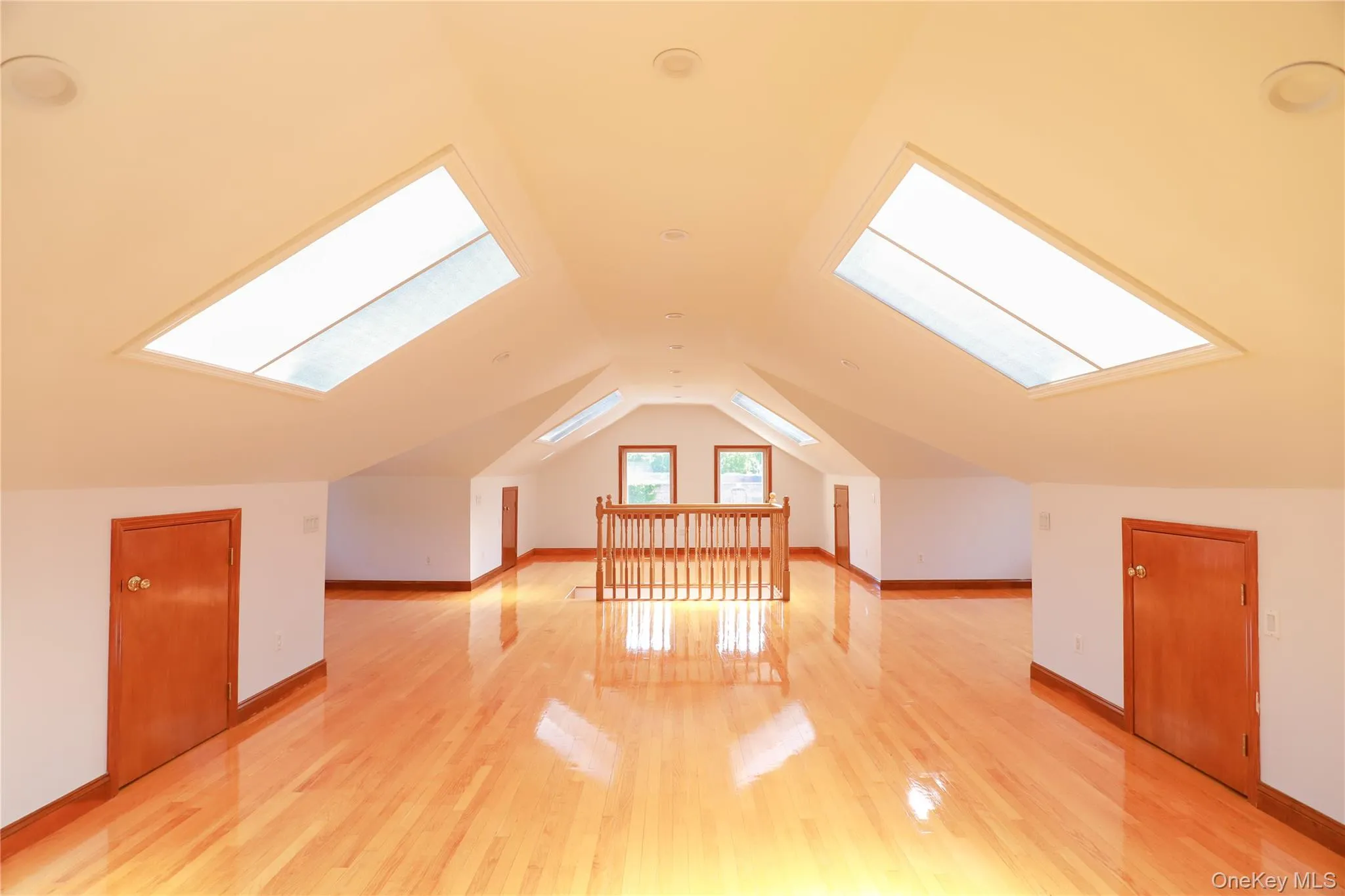 Expansive attic space featuring polished wood-finish flooring, multiple skylights, and dormer windows Expansive attic space featuring polished wood-finish flooring, multiple skylights, and dormer windows