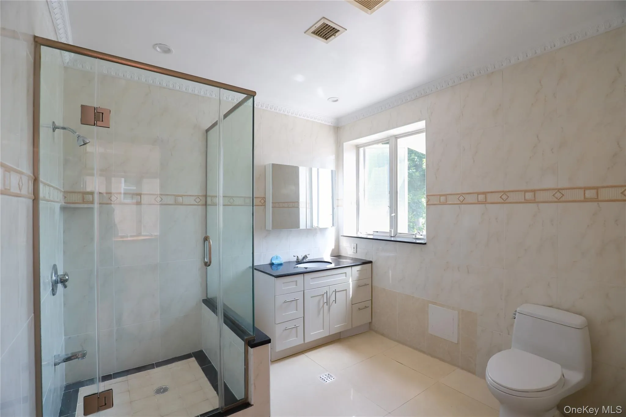 Glass-enclosed shower with a black base and light-toned tile flooring Glass-enclosed shower with a black base and light-toned tile flooring