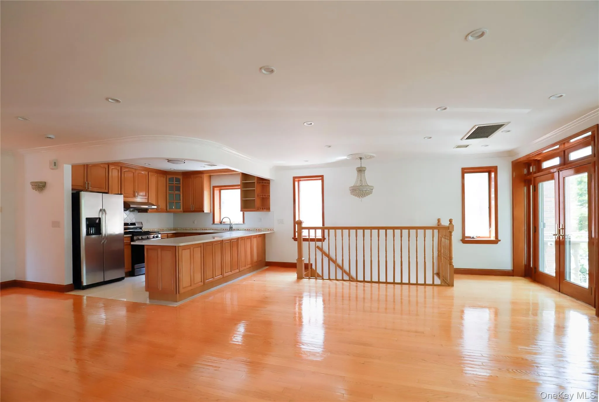 Expansive open-concept living area featuring light wood-finish flooring, recessed lighting, and a polished chandelier Expansive open-concept living area featuring light wood-finish flooring, recessed lighting, and a polished chandelier