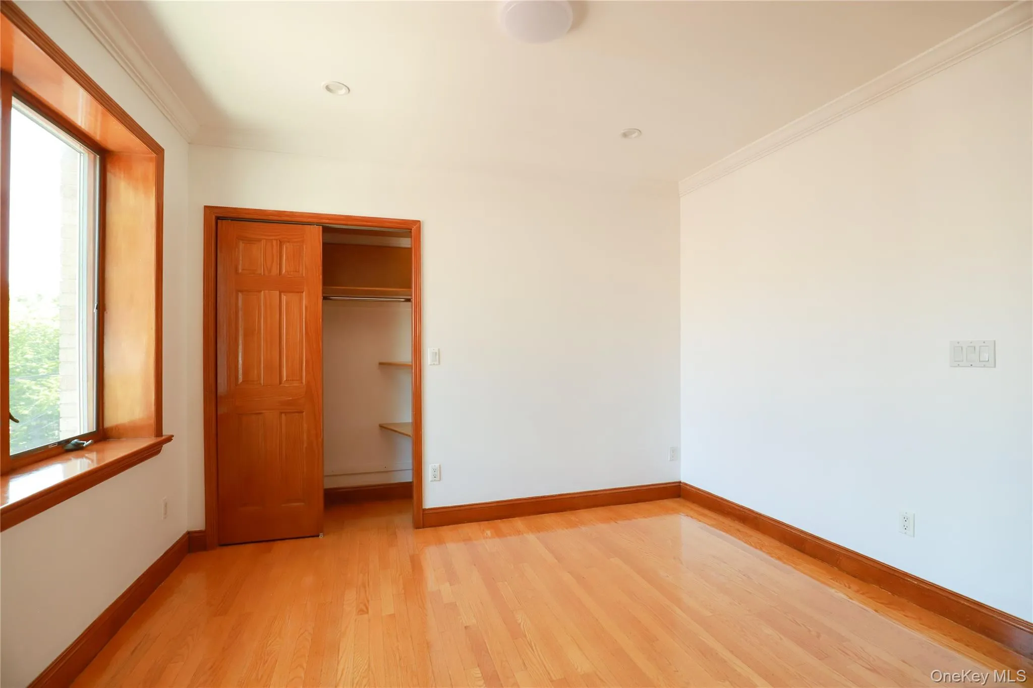 Room featuring wood-finish flooring, white walls, and crown molding Room featuring wood-finish flooring, white walls, and crown molding