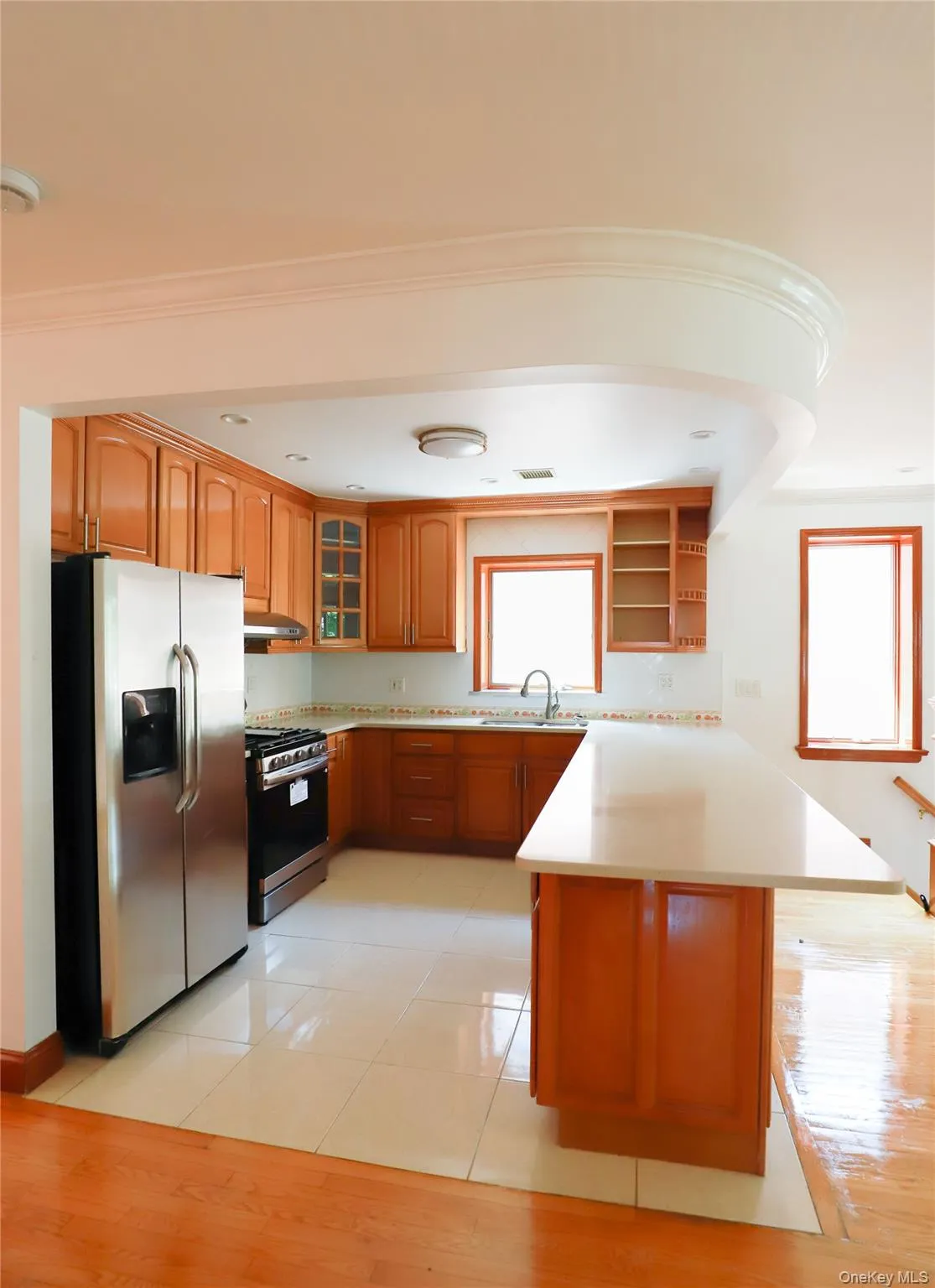Kitchen featuring wood cabinetry, stainless steel appliances, and a light-toned countertop Kitchen featuring wood cabinetry, stainless steel appliances, and a light-toned countertop