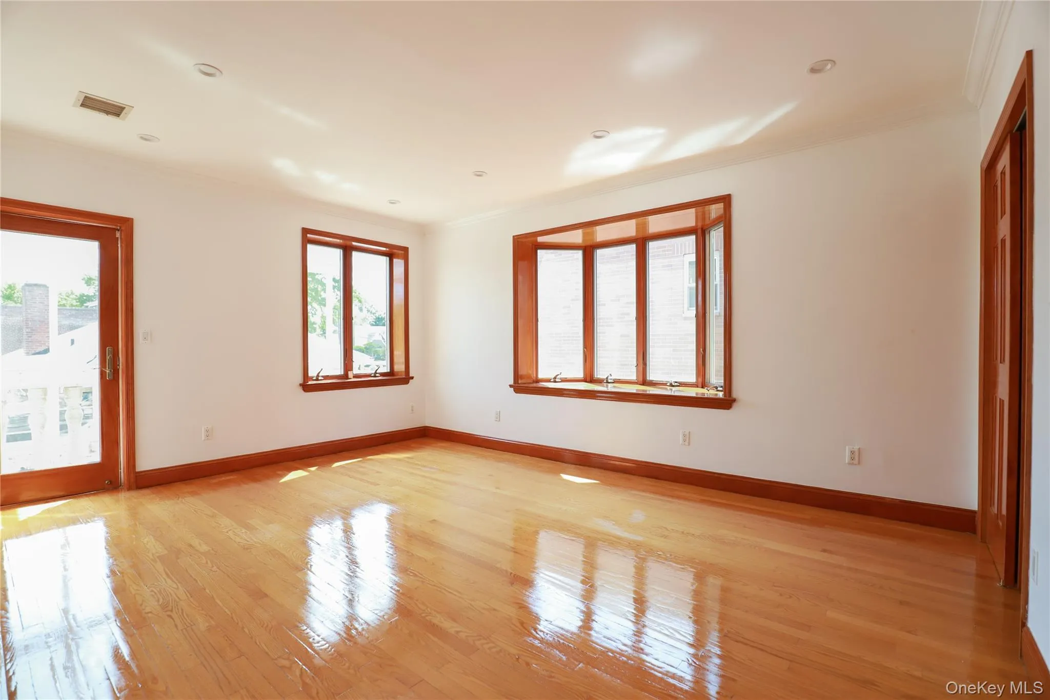 Hardwood flooring throughout featuring a bay window, additional window, and a glass-paneled door Hardwood flooring throughout featuring a bay window, additional window, and a glass-paneled door