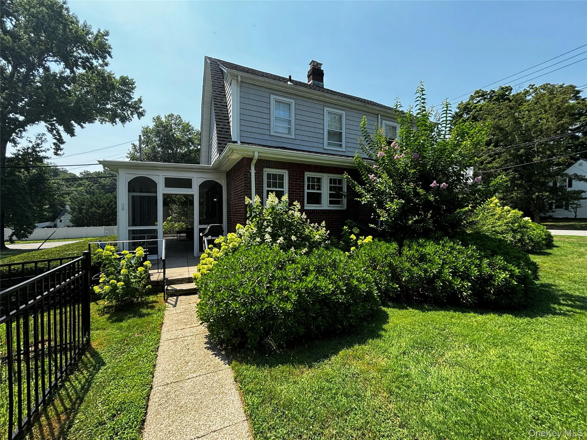 Rear view of house featuring a chimney, brick siding, a sunroom, a yard, and fence Rear view of house featuring a chimney, brick siding, a sunroom, a yard, and fence
