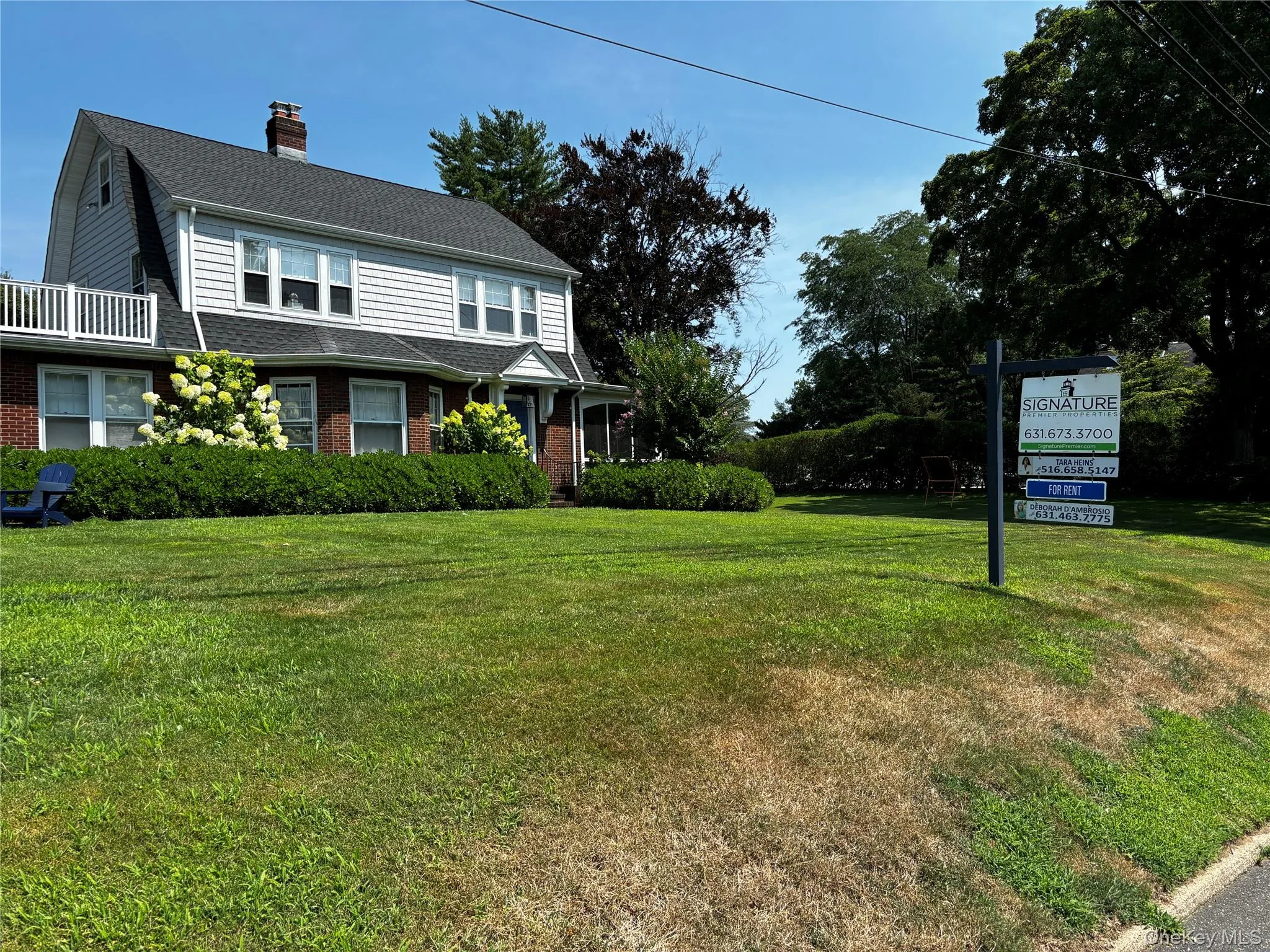 Colonial inspired home featuring roof with shingles, a chimney, a front lawn, and brick siding Colonial inspired home featuring roof with shingles, a chimney, a front lawn, and brick siding