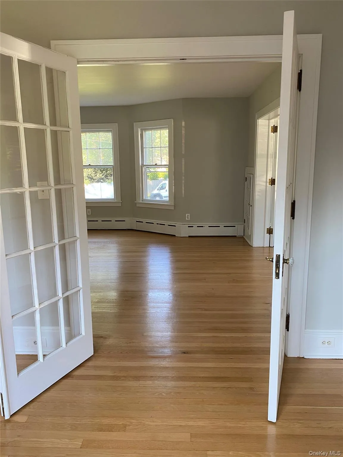 Empty room with light wood-style floors, baseboards, and baseboard heating Empty room with light wood-style floors, baseboards, and baseboard heating
