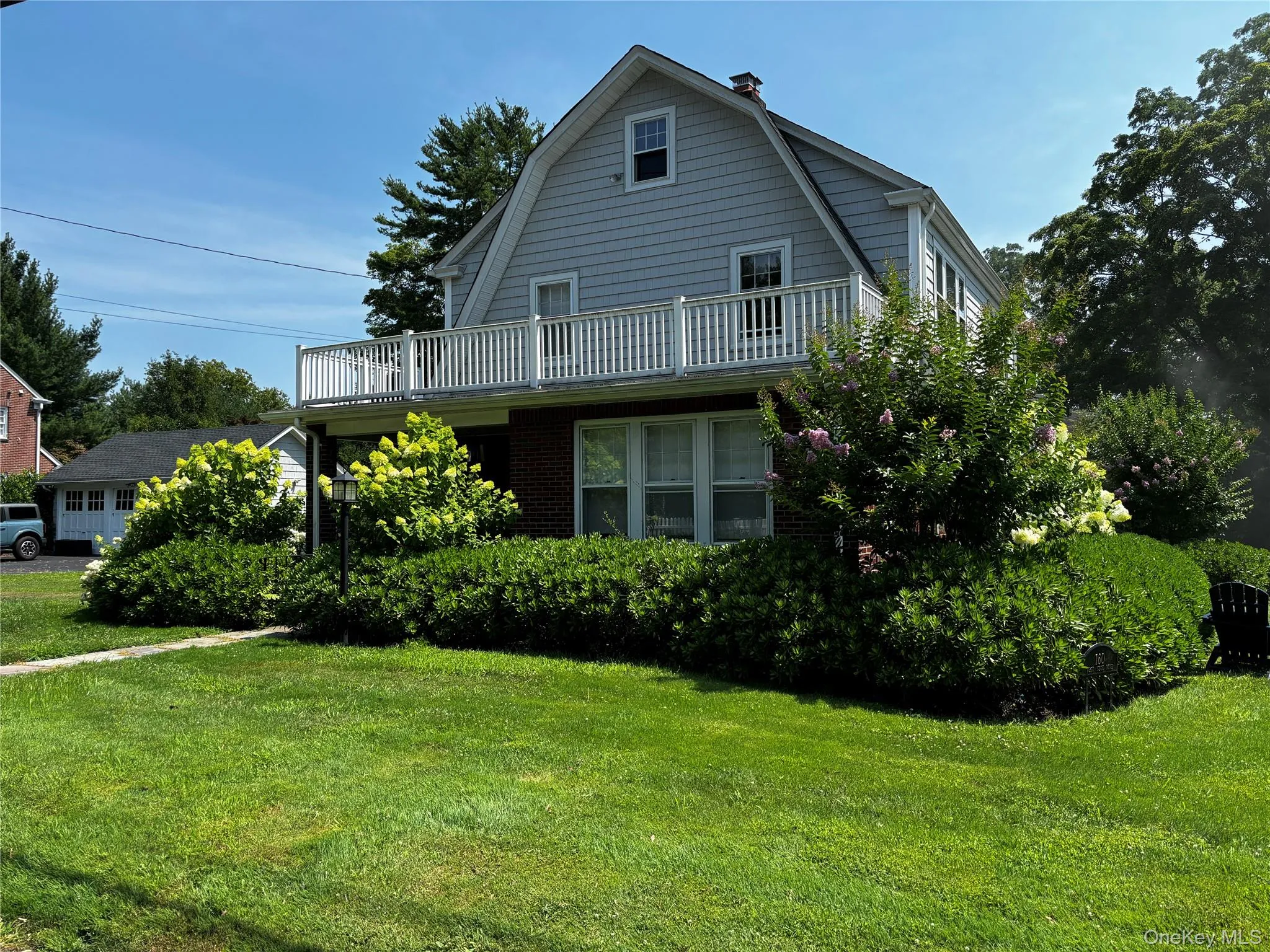View of front facade with a gambrel roof, a chimney, and a front lawn View of front facade with a gambrel roof, a chimney, and a front lawn