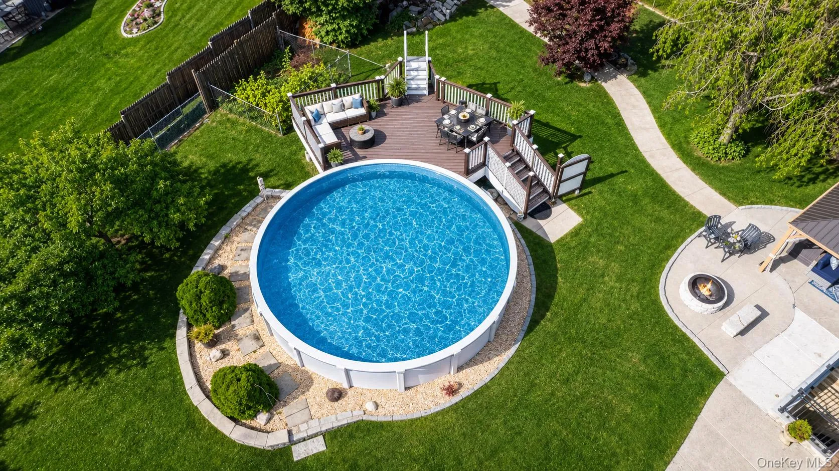 Another angle of the inviting backyard featuring an above-ground swimming pool and patio with fire pit Another angle of the inviting backyard featuring an above-ground swimming pool and patio with fire pit