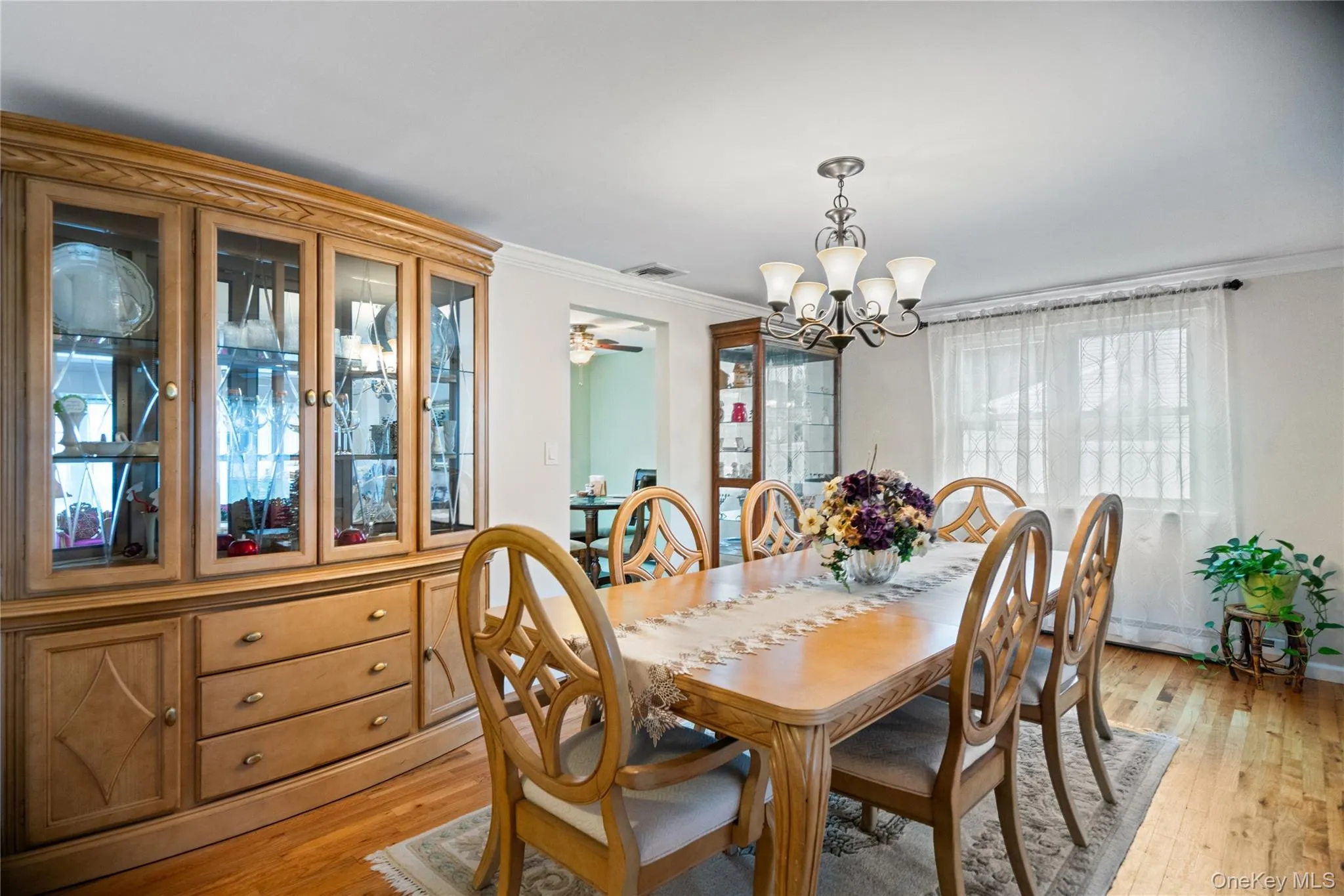 Dining area featuring wood-finish flooring, a contemporary chandelier, and ample natural light from multiple windows Dining area featuring wood-finish flooring, a contemporary chandelier, and ample natural light from multiple windows