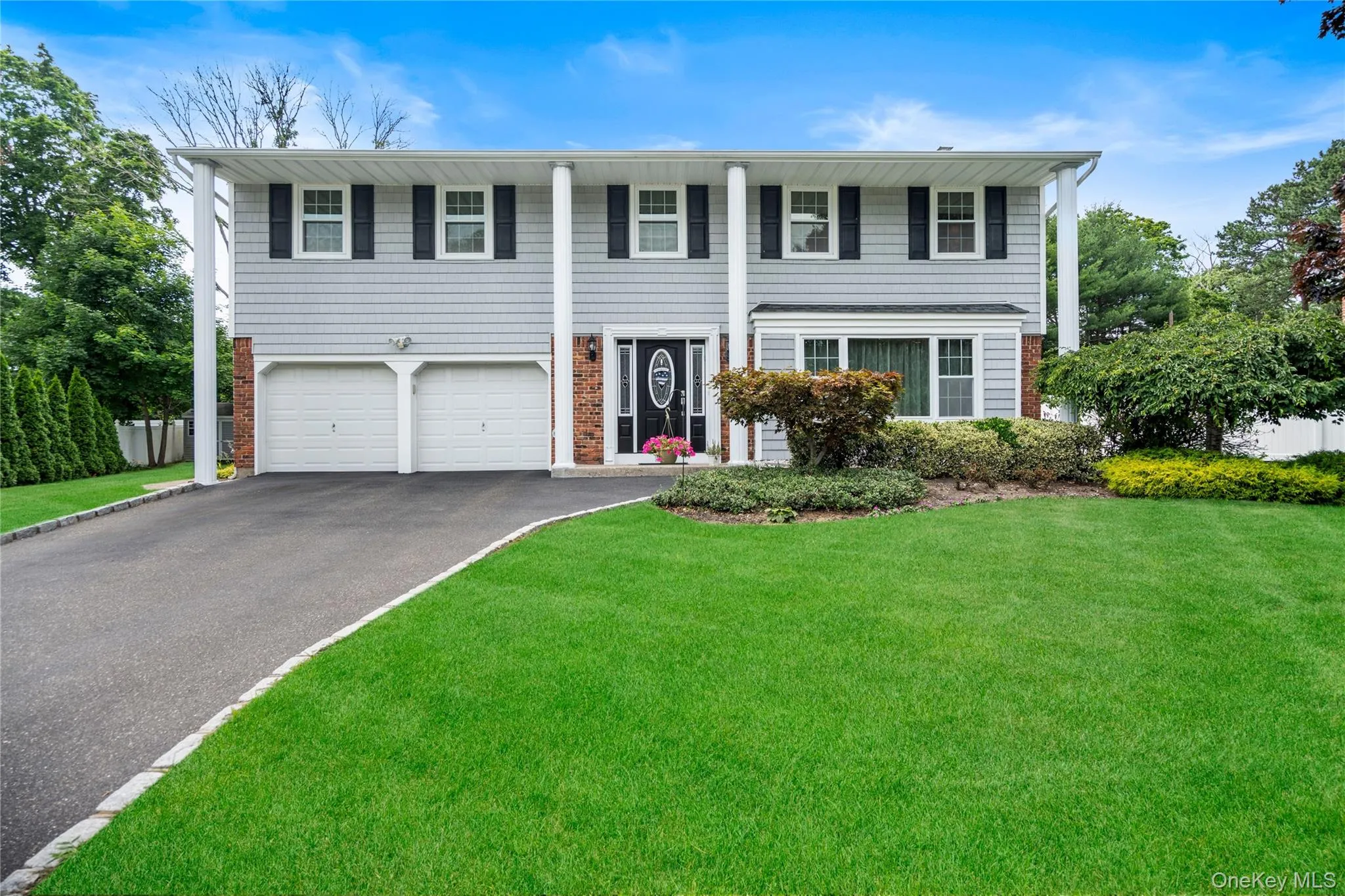 Two-story residence featuring light gray siding, dark brick accents, and a dual garage Two-story residence featuring light gray siding, dark brick accents, and a dual garage
