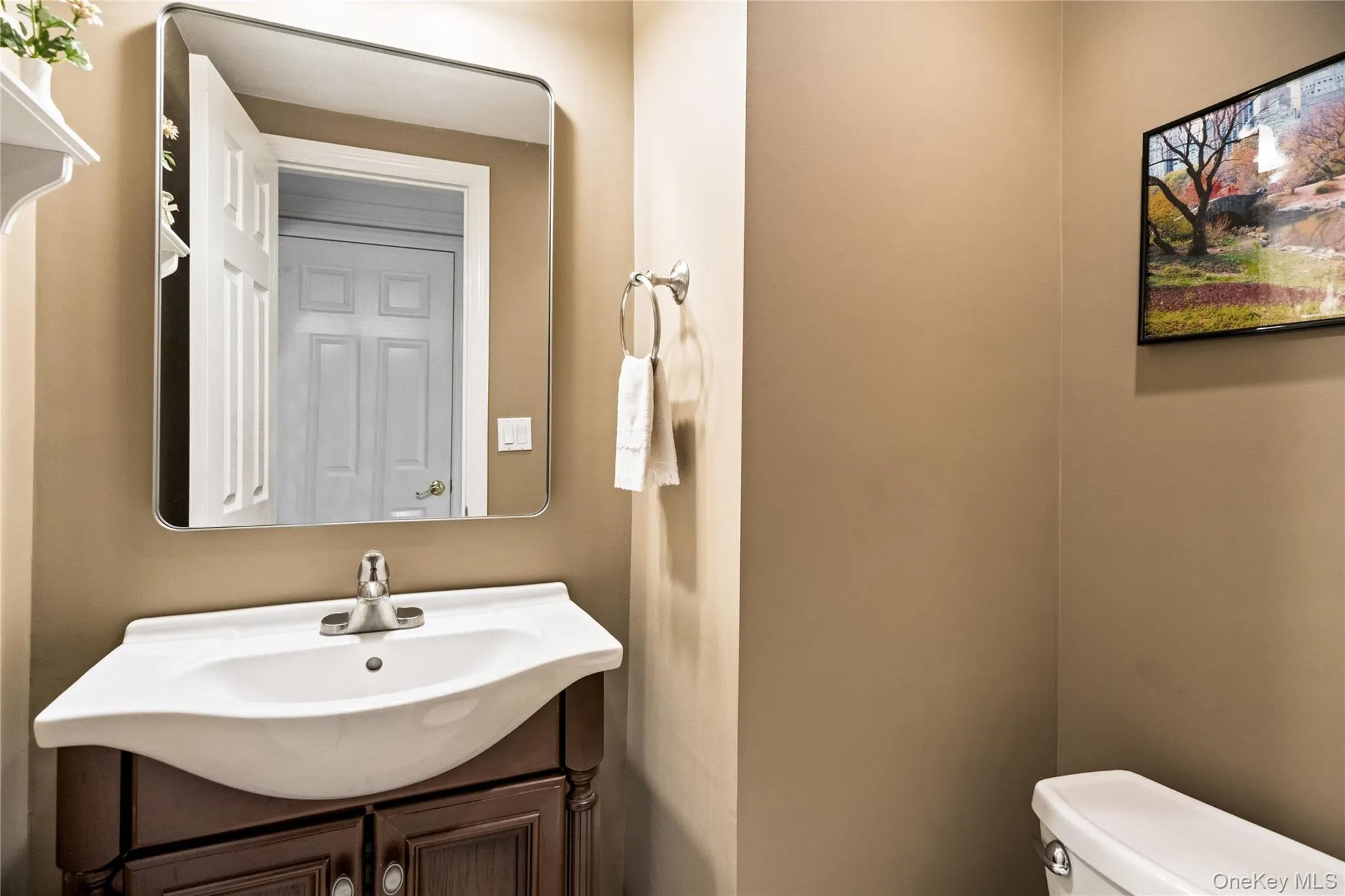 Bathroom vanity featuring a white porcelain sink with chrome faucet, set atop a dark wood-finish cabinet with double doors Bathroom vanity featuring a white porcelain sink with chrome faucet, set atop a dark wood-finish cabinet with double doors