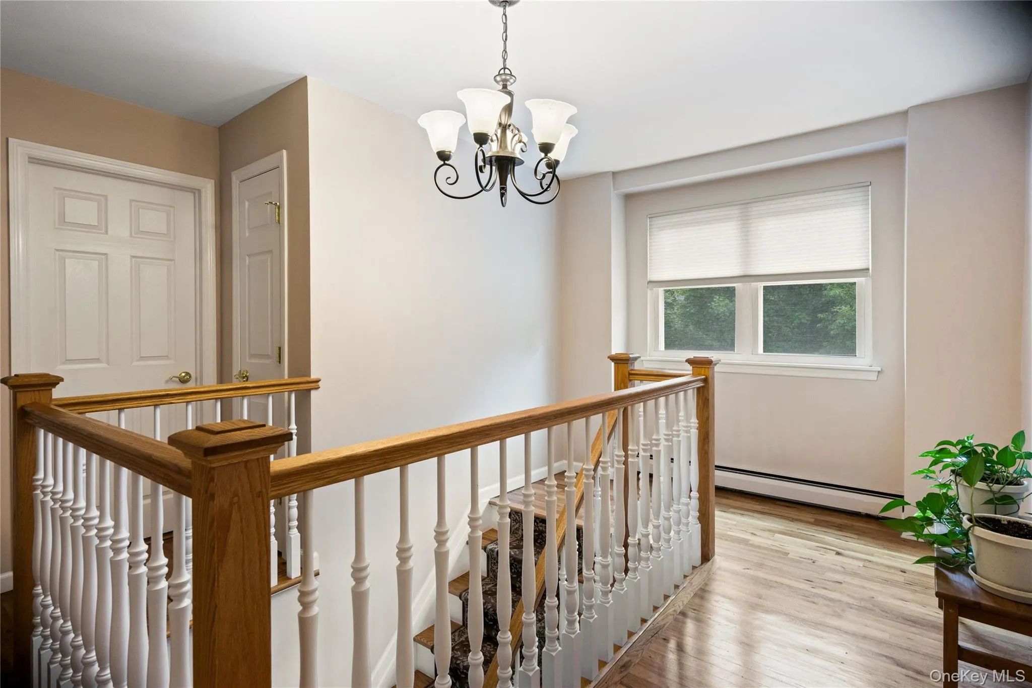 Upper landing featuring hardwood flooring, a chandelier, and a window with natural light Upper landing featuring hardwood flooring, a chandelier, and a window with natural light