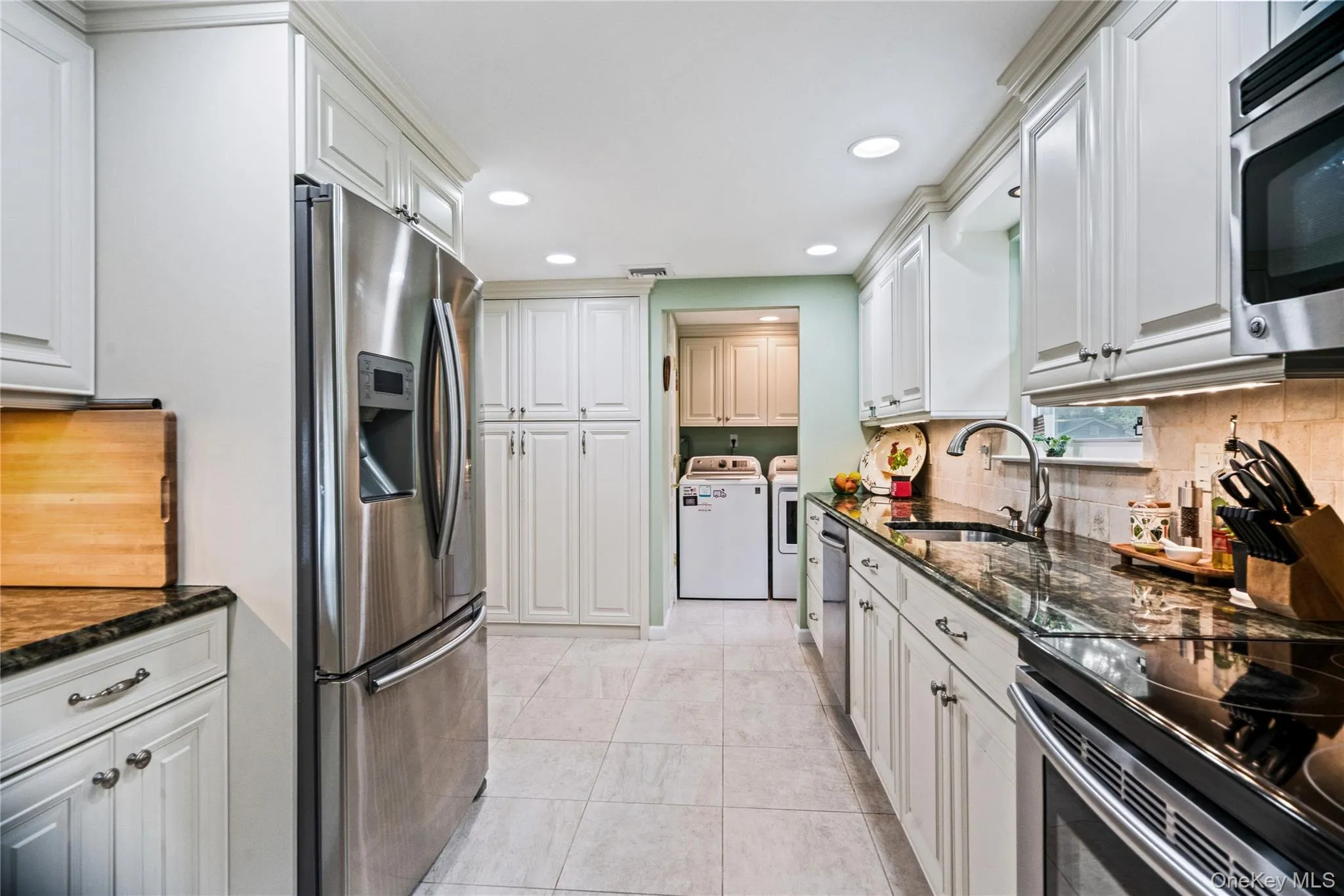 Kitchen featuring white shaker-style cabinetry, dark stone countertops, stainless steel appliances, and recessed lighting Kitchen featuring white shaker-style cabinetry, dark stone countertops, stainless steel appliances, and recessed lighting