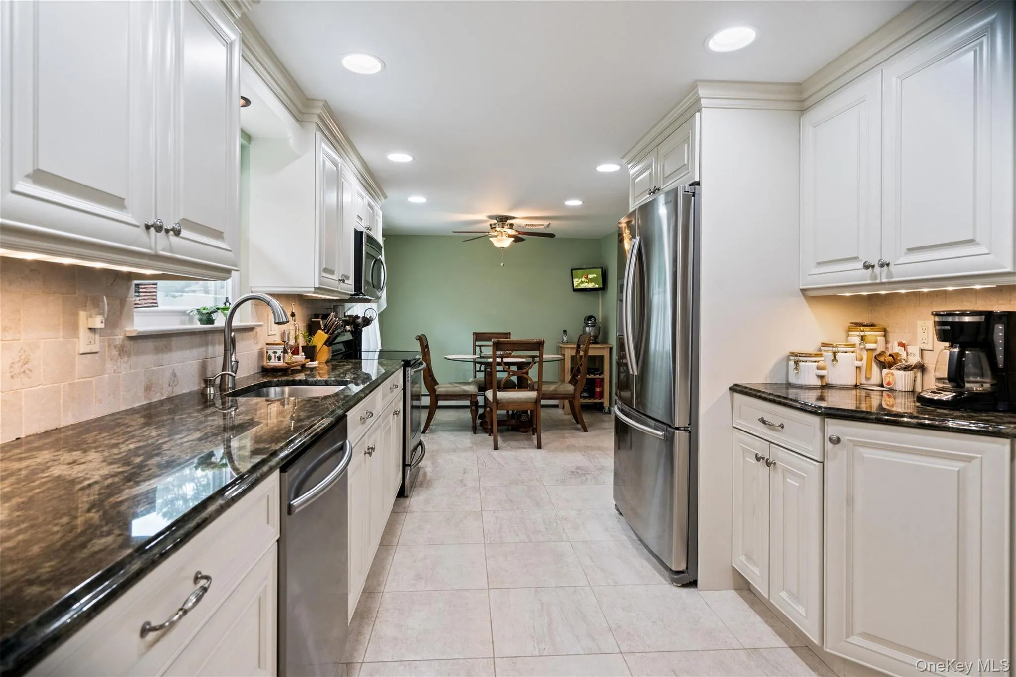 Kitchen featuring white cabinetry, dark stone countertops, stainless steel appliances, tile flooring, and recessed lighting Kitchen featuring white cabinetry, dark stone countertops, stainless steel appliances, tile flooring, and recessed lighting