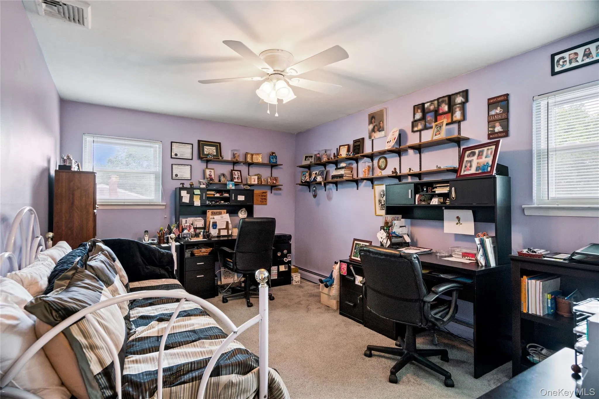 Room featuring two windows with blinds, a ceiling fan, and wall-mounted shelving Room featuring two windows with blinds, a ceiling fan, and wall-mounted shelving