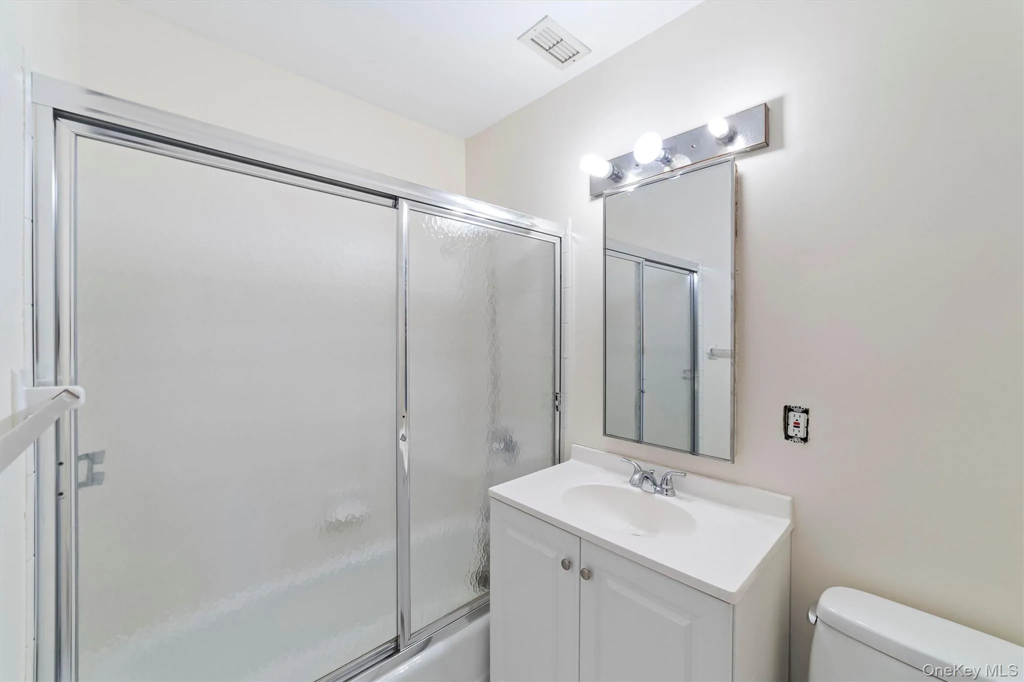 Full bathroom with vanity, shower / bath combination with glass door, and toilet on upper level. Full bathroom with vanity, shower / bath combination with glass door, and toilet on upper level.