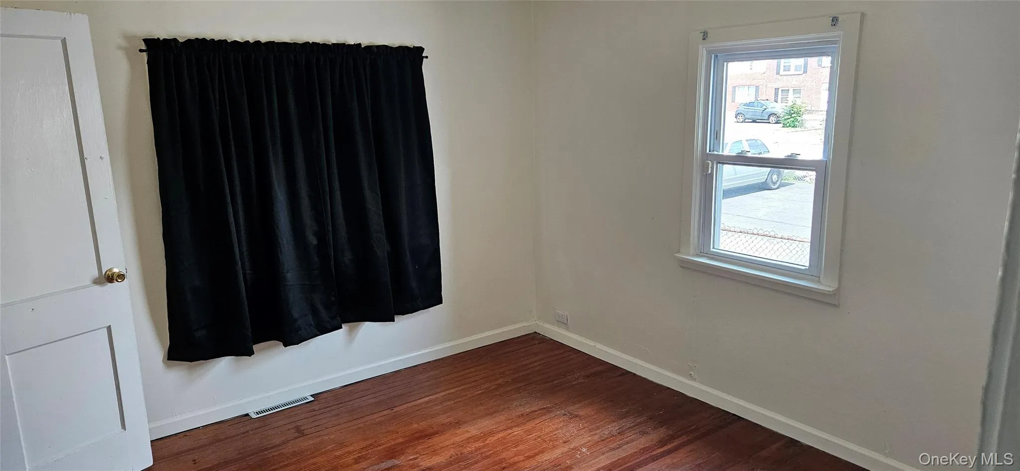 Interior room featuring wood-finish flooring, white baseboards, and light-toned walls Interior room featuring wood-finish flooring, white baseboards, and light-toned walls