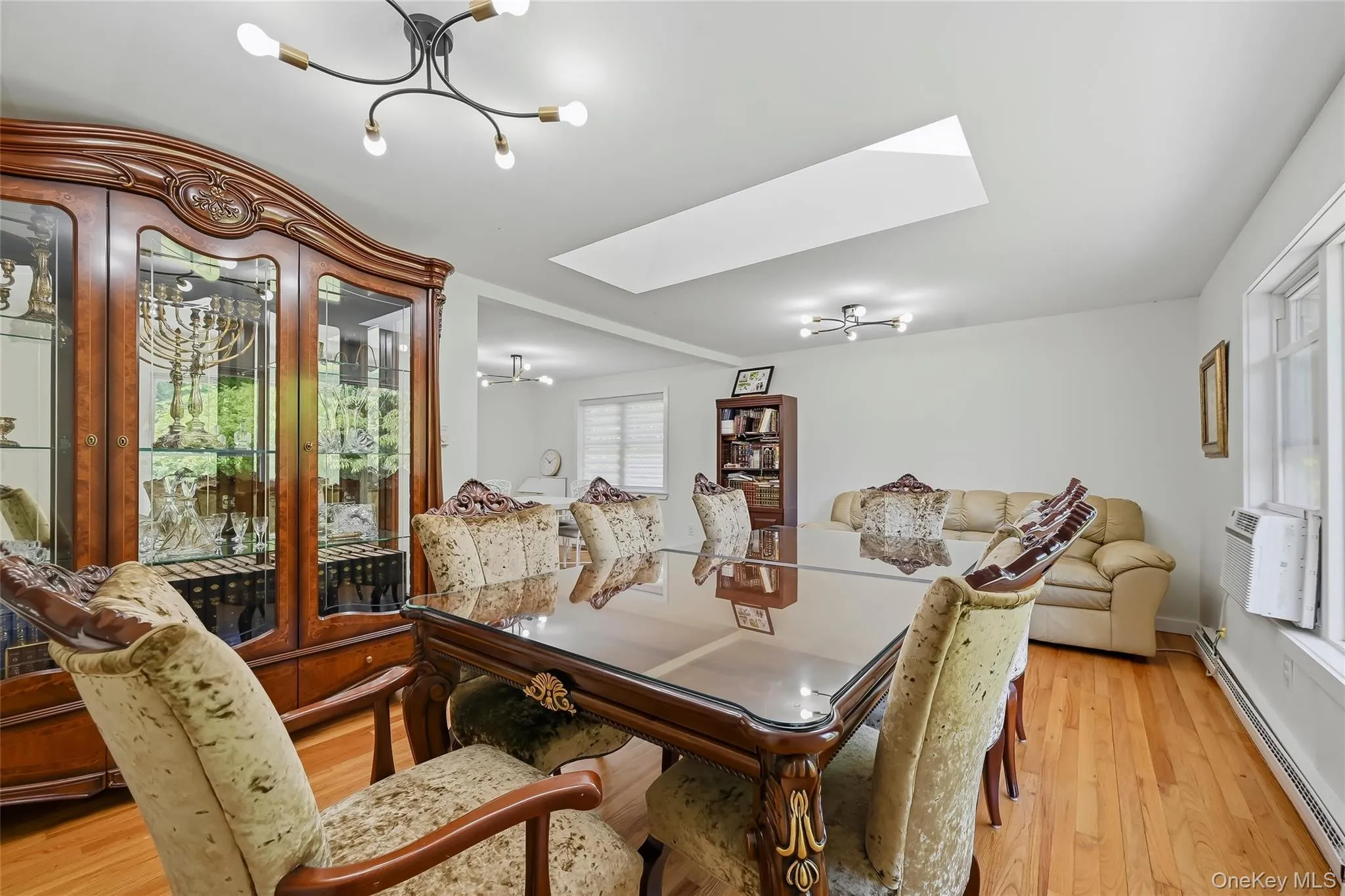 Hardwood flooring throughout a bright room featuring a ceiling-mounted light fixture and a skylight Hardwood flooring throughout a bright room featuring a ceiling-mounted light fixture and a skylight