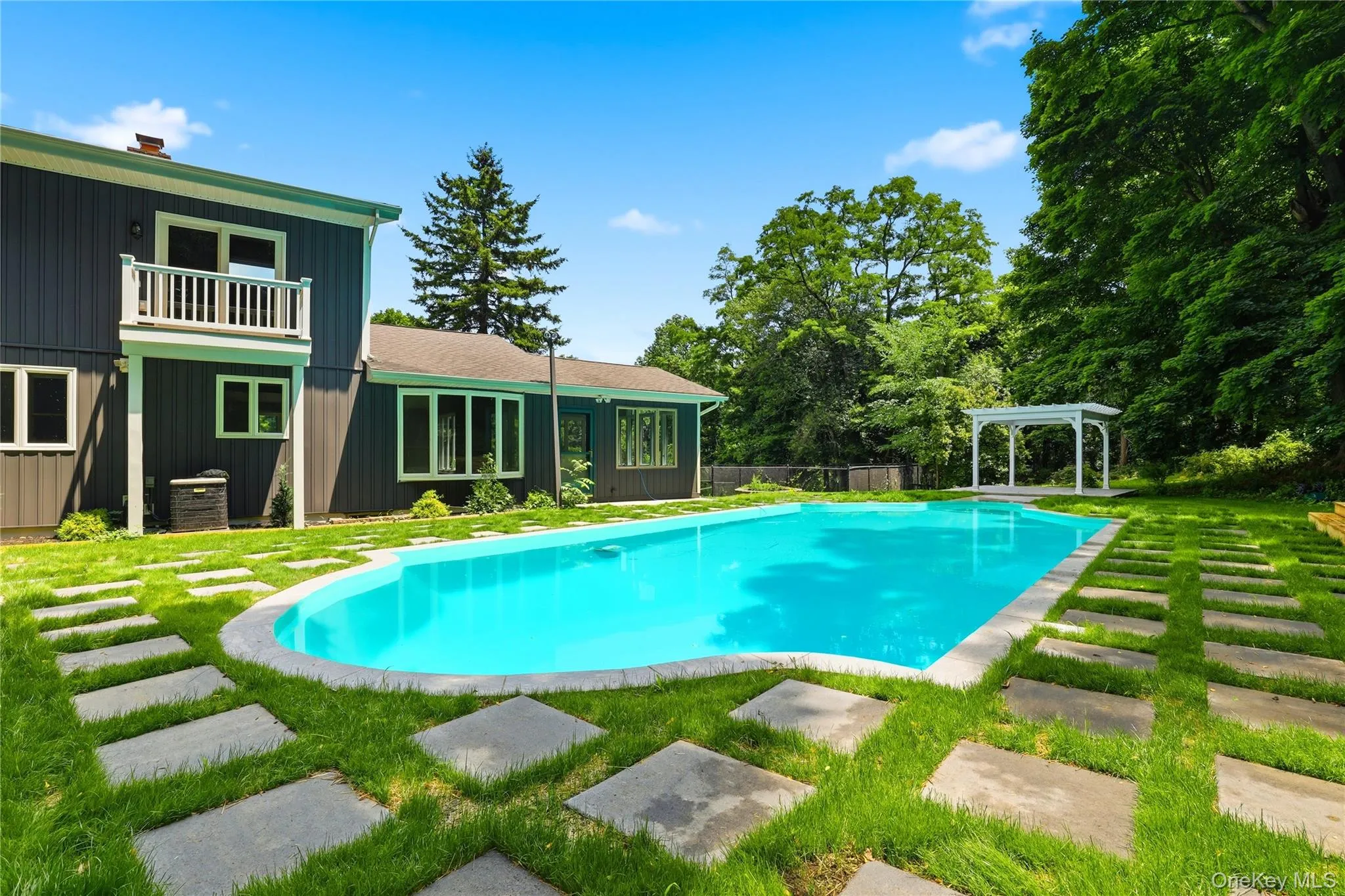 Inviting in-ground swimming pool with a stone coping and a white pergola Inviting in-ground swimming pool with a stone coping and a white pergola