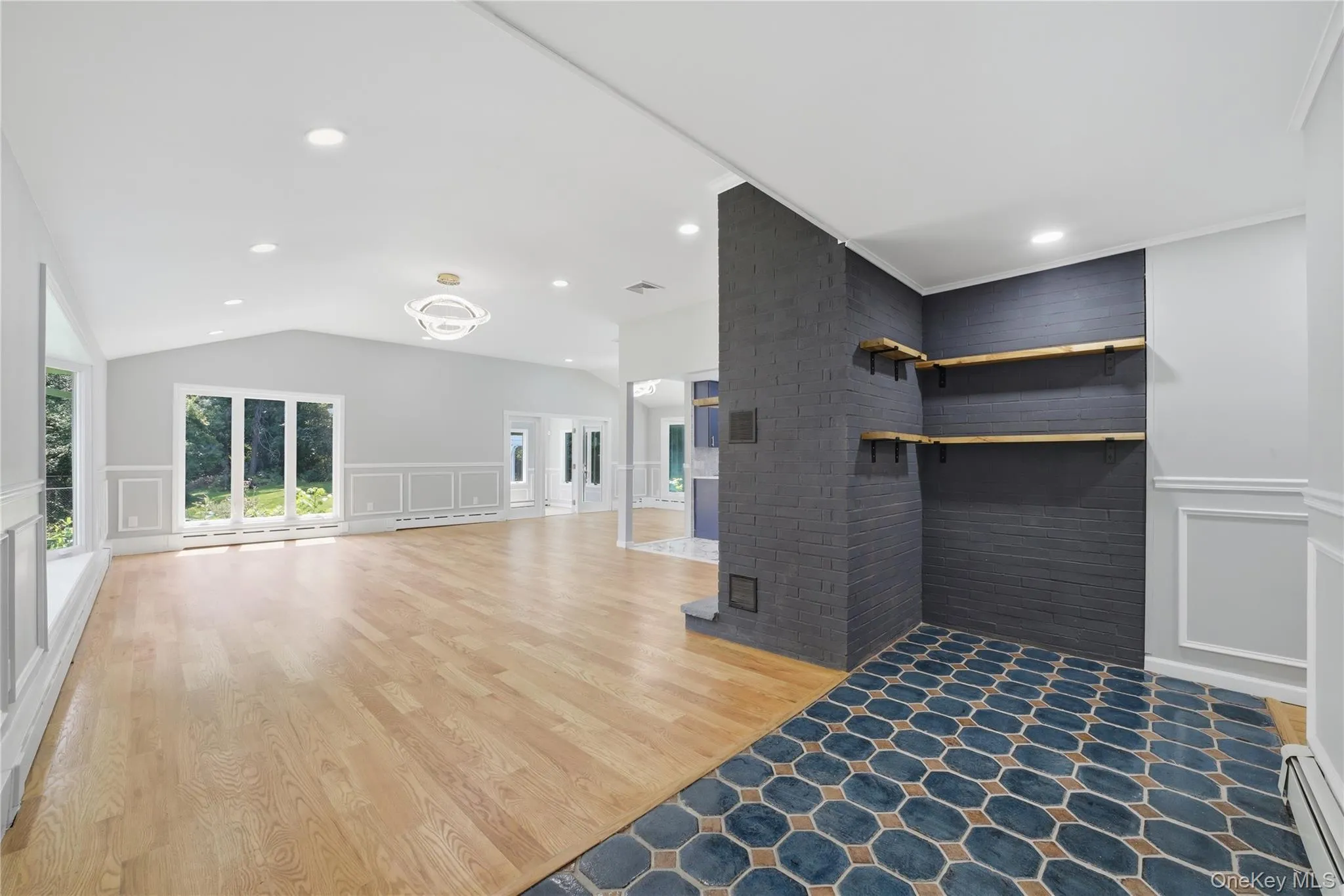 Entry foyer featuring hexagonal floor tiling, leading to a spacious living area with wood-finish flooring and a hallway to the rest of the main floor. Entry foyer featuring hexagonal floor tiling, leading to a spacious living area with wood-finish flooring and a hallway to the rest of the main floor.
