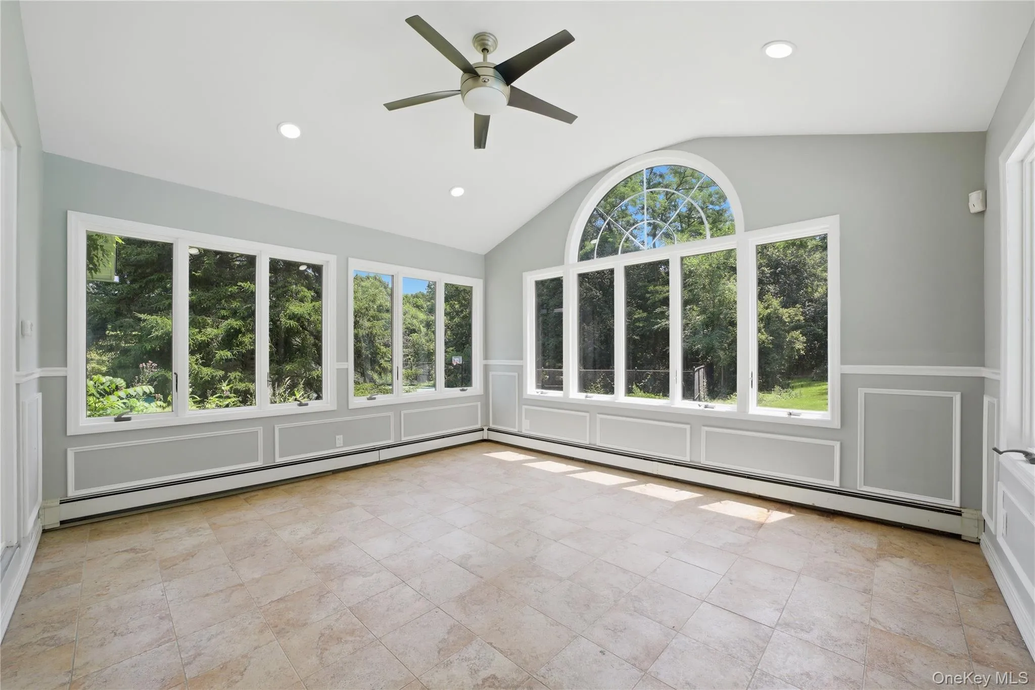 Light-filled room featuring large windows, a vaulted ceiling, recessed lighting, a ceiling fan, and tile flooring Light-filled room featuring large windows, a vaulted ceiling, recessed lighting, a ceiling fan, and tile flooring