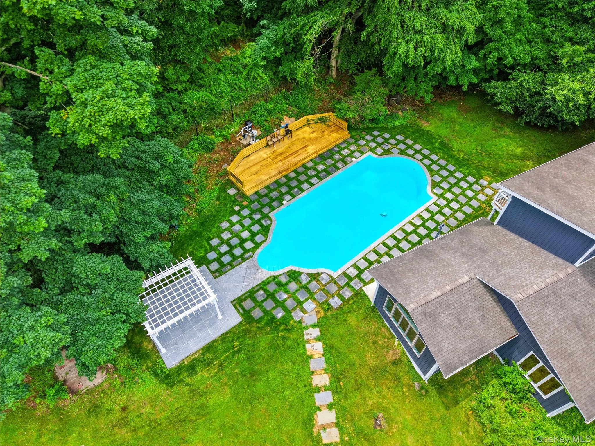 In-ground swimming pool with geometric paving, surrounded by lush green lawn In-ground swimming pool with geometric paving, surrounded by lush green lawn