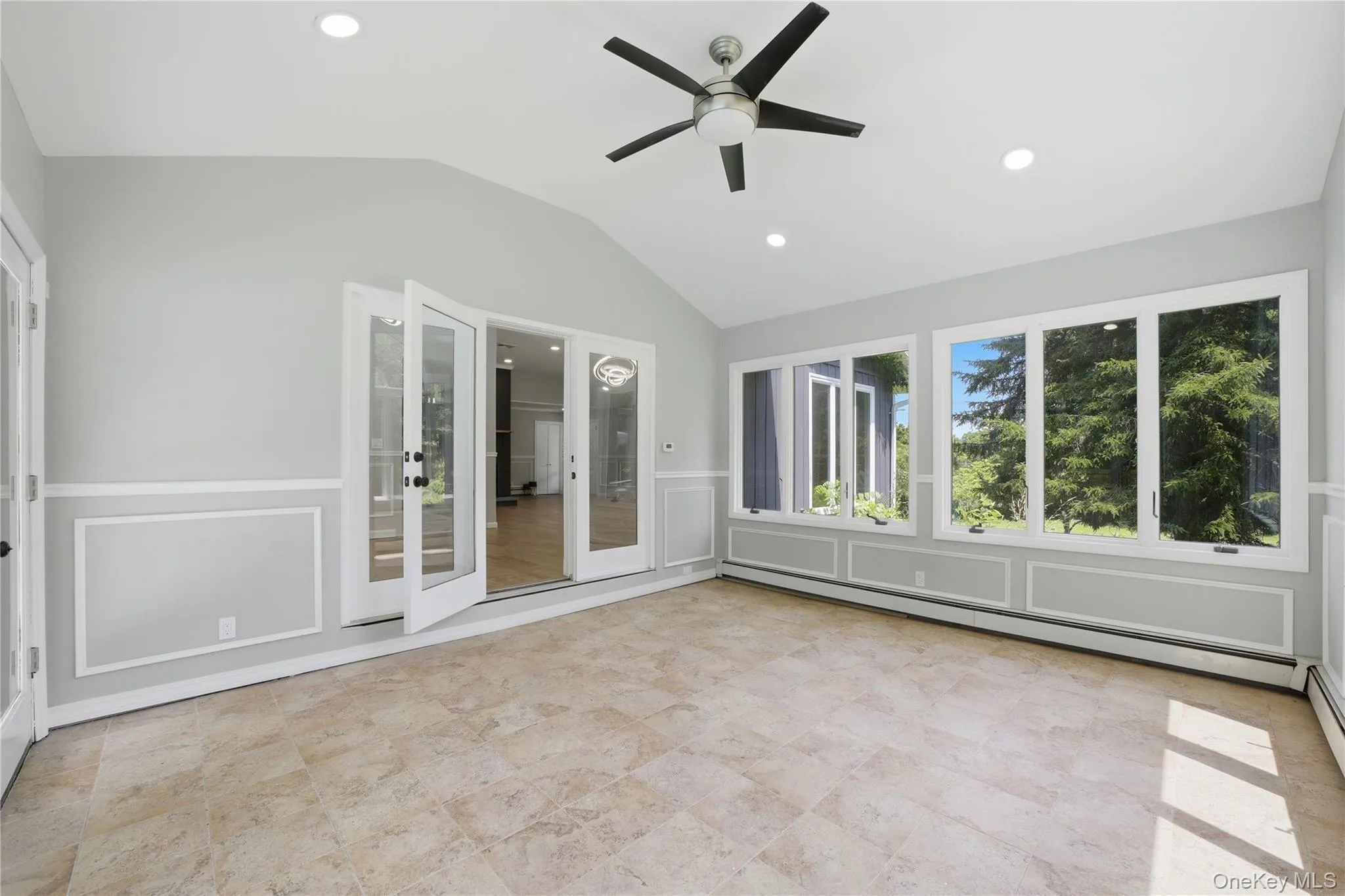 Light-filled room featuring large windows, a vaulted ceiling, recessed lighting, a ceiling fan, and tile flooring Light-filled room featuring large windows, a vaulted ceiling, recessed lighting, a ceiling fan, and tile flooring
