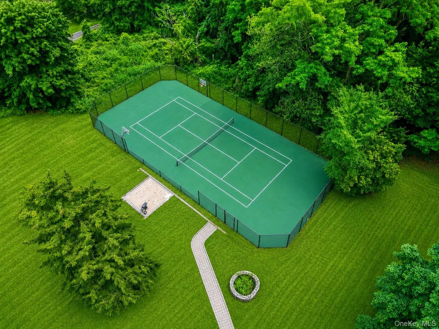 Private tennis court/basketball court with green hard-surface playing area and perimeter fencing Private tennis court/basketball court with green hard-surface playing area and perimeter fencing