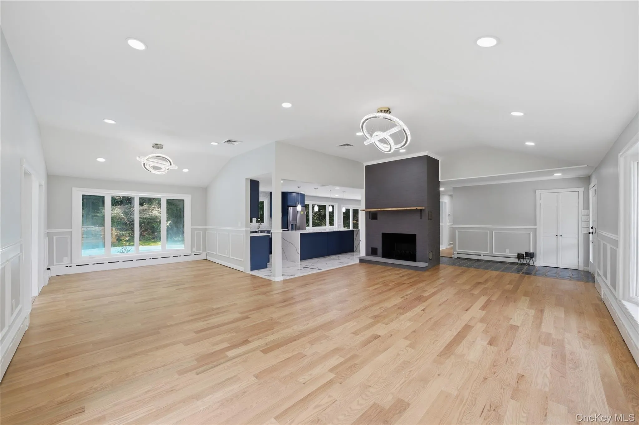 Spacious interior featuring wood-finish flooring, a fireplace with a dark mantel, and recessed lighting Spacious interior featuring wood-finish flooring, a fireplace with a dark mantel, and recessed lighting